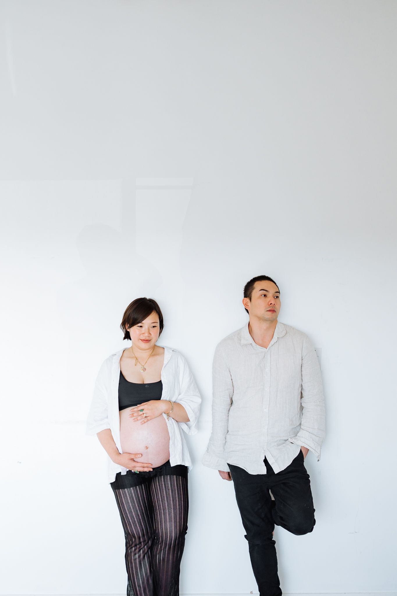 Contemporary studio photoshoot featuring two people in black and white outfits against light background.