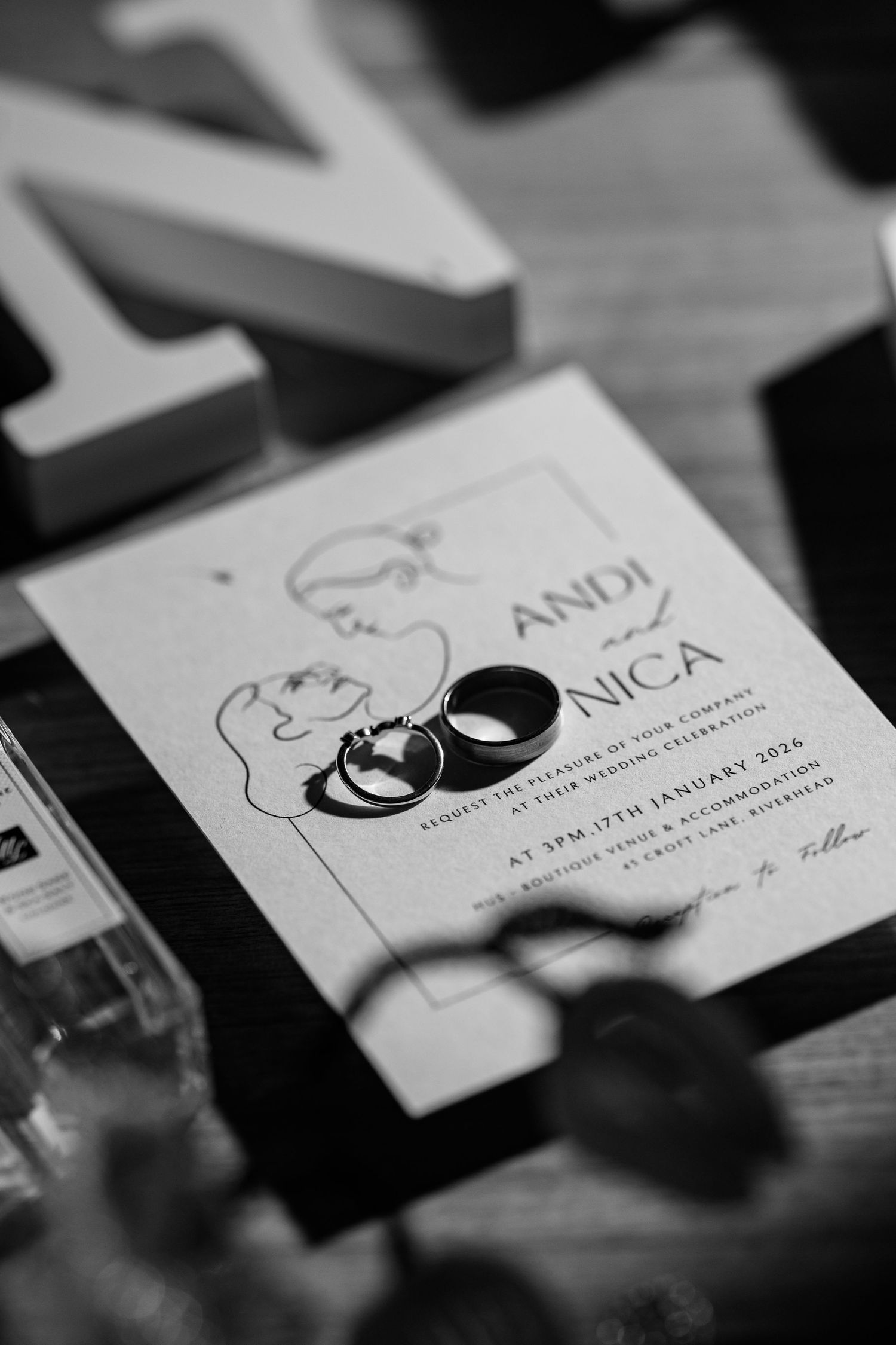 Wedding invitation cards with elegant design and wedding rings displayed in black and white.