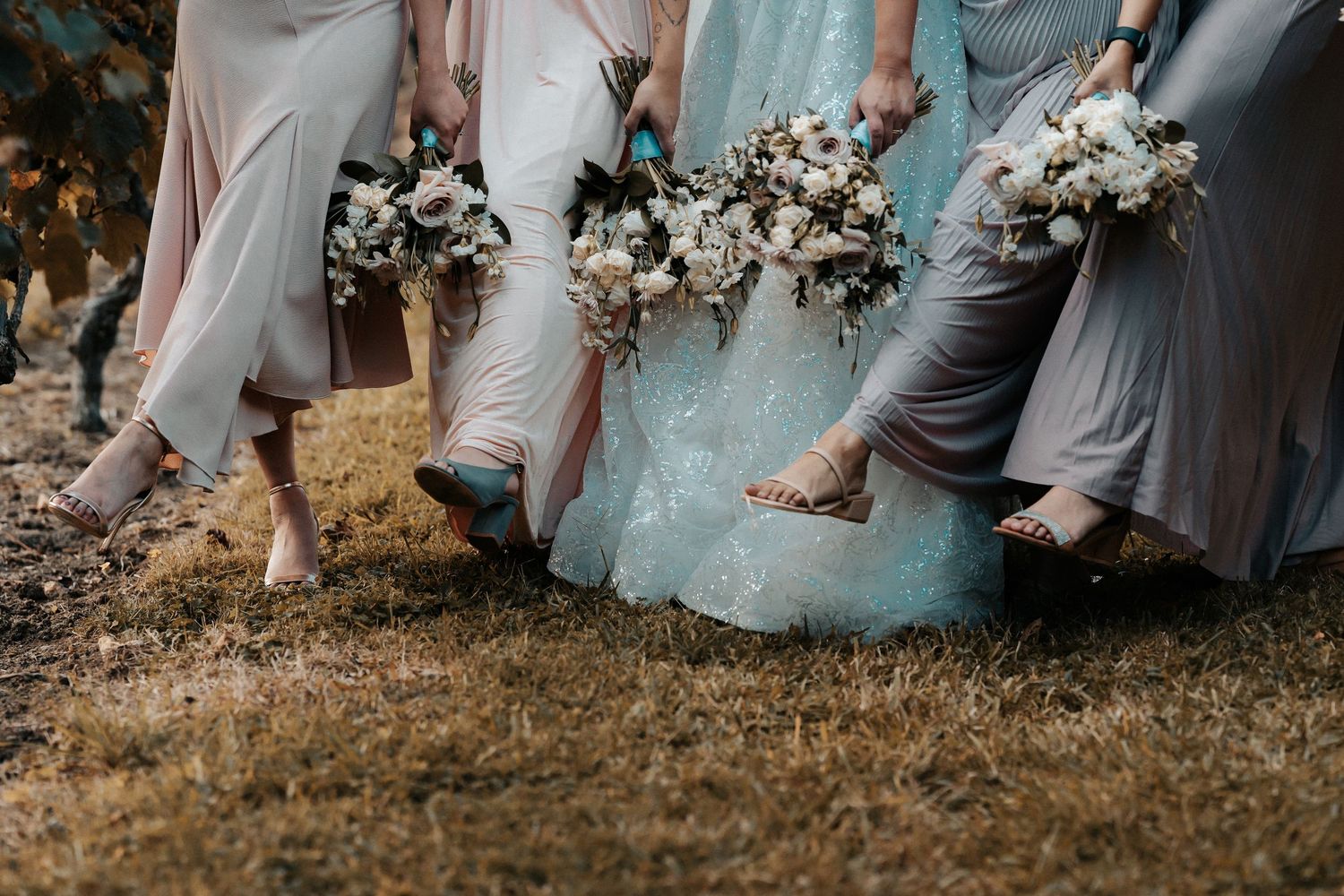 Wedding party in soft pastel dresses walking together outdoors.