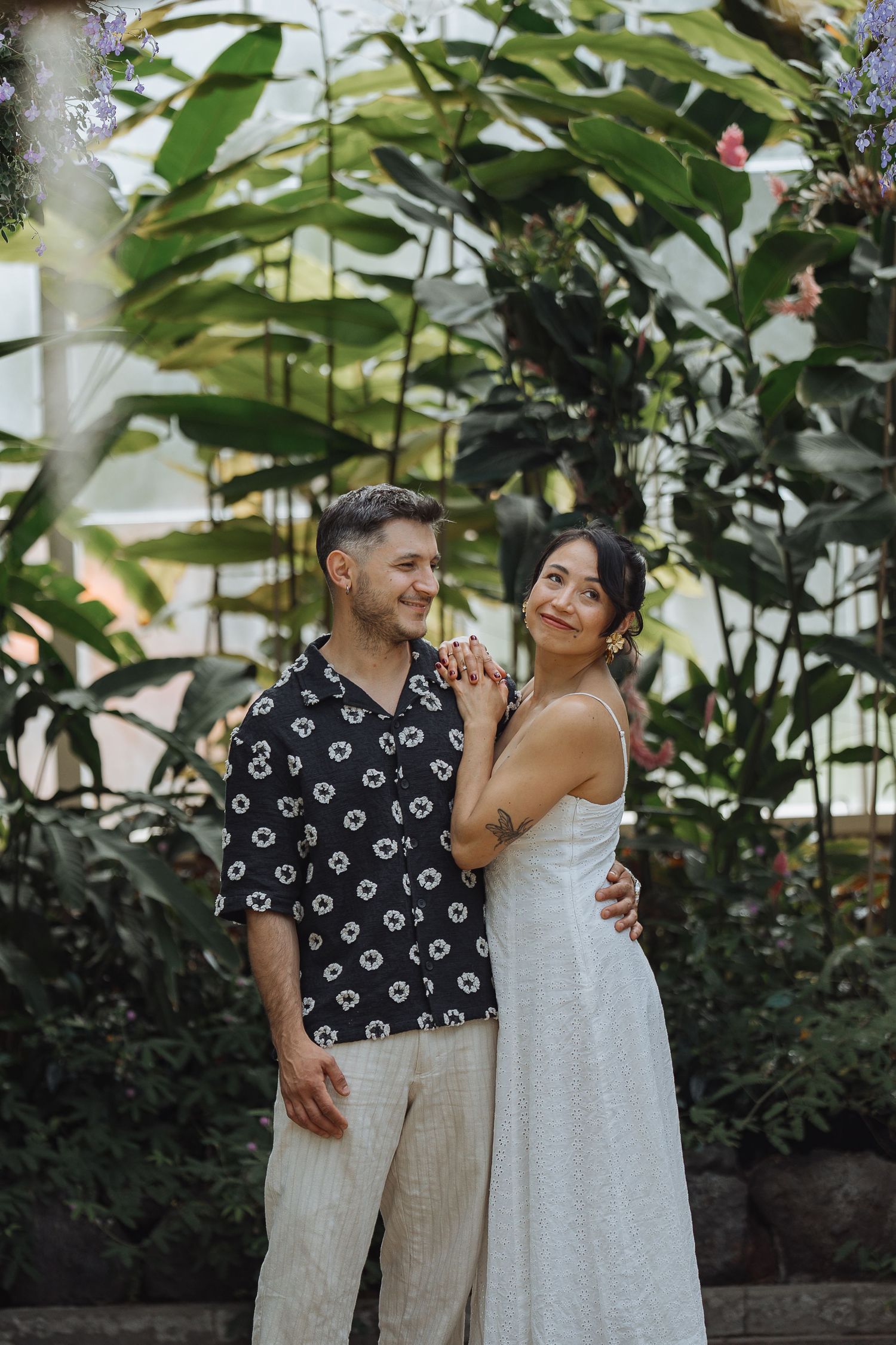 Happy couple embracing in a garden setting with tropical plants and greenery.