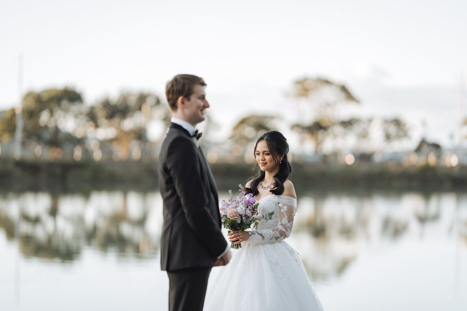 Elegant waterfront wedding portraits with reflections in a serene lake backdrop.