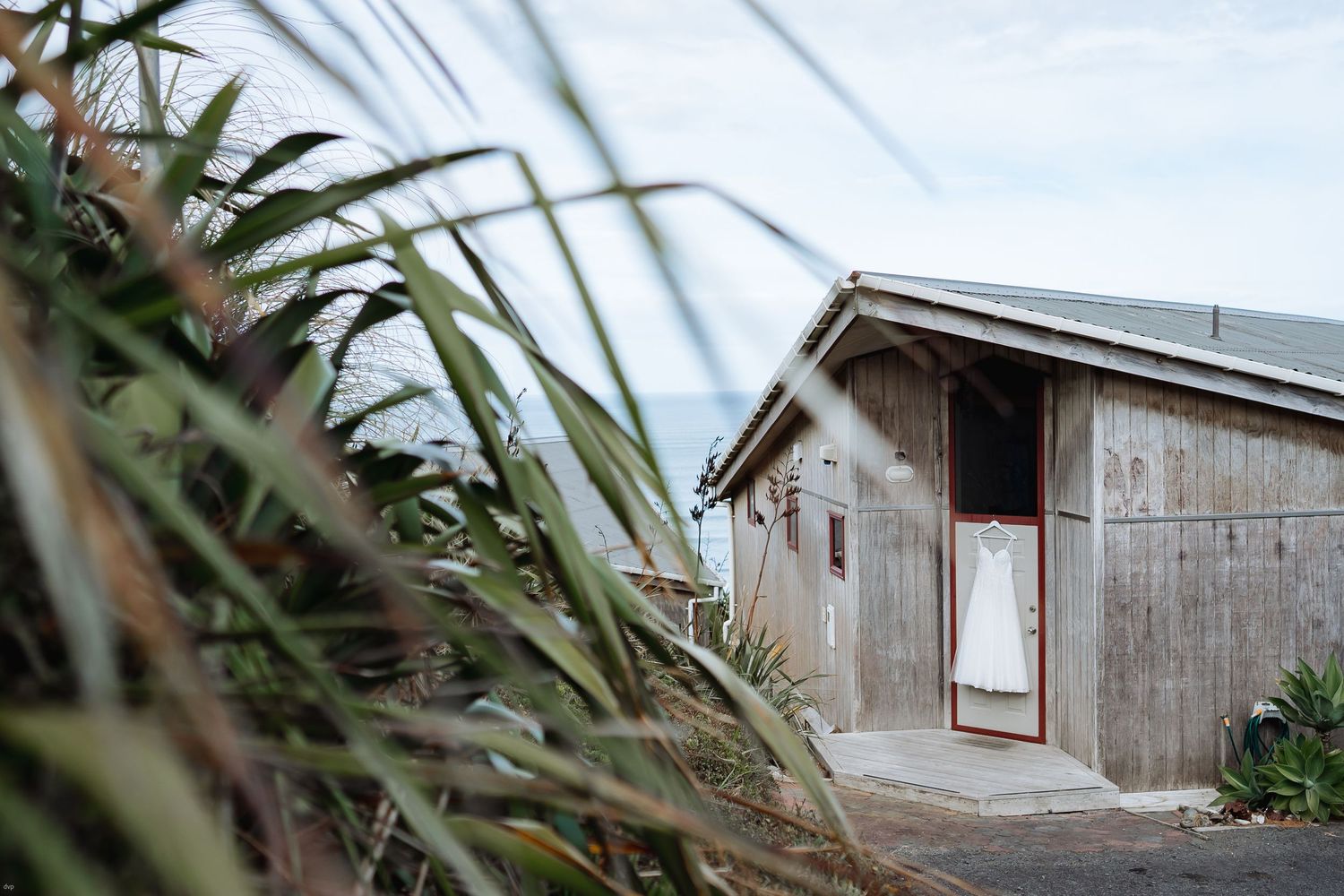 Rustic wooden buildings and palm fronds create natural wedding venue backdrop.