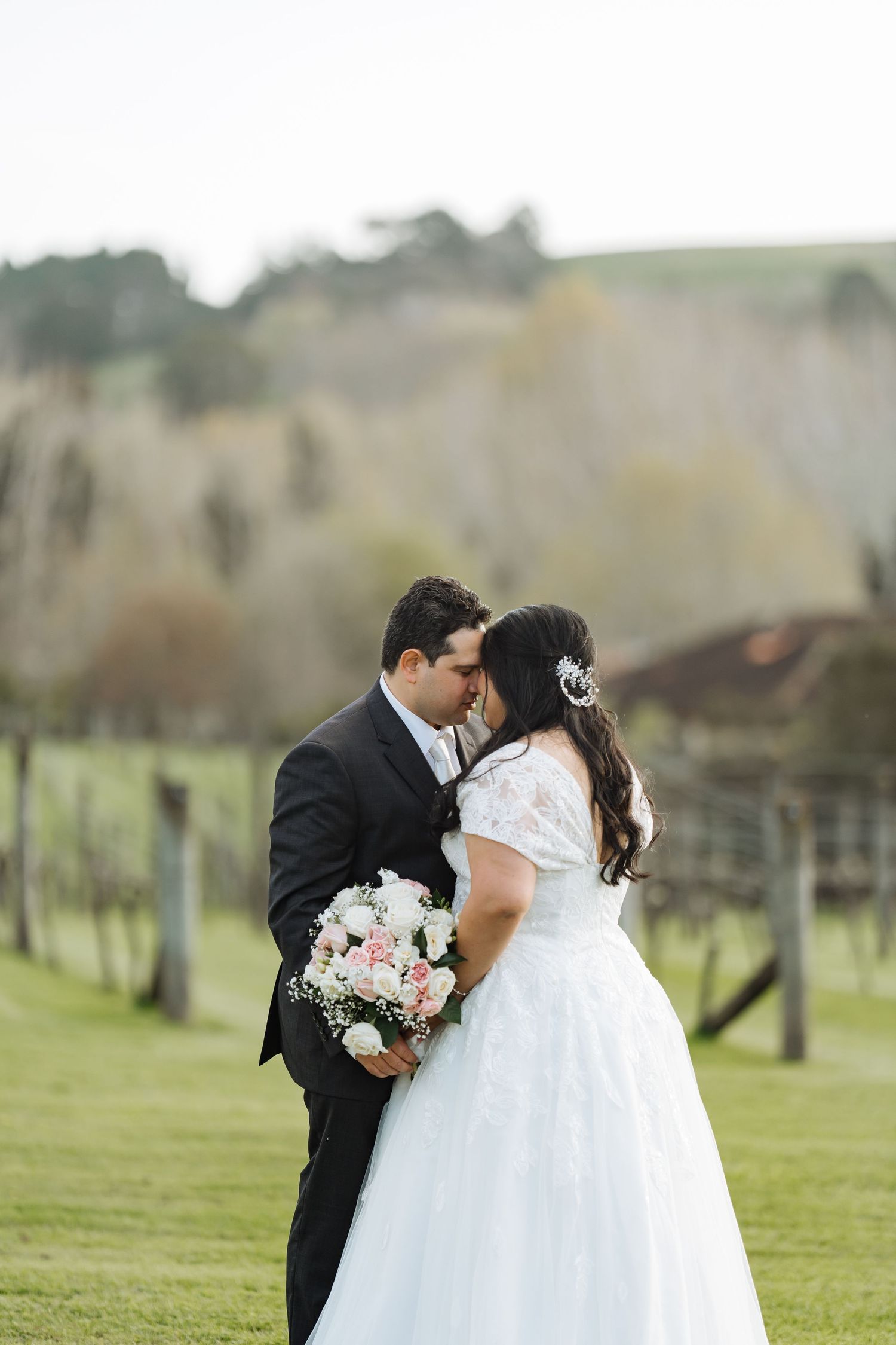 Newlyweds sharing a romantic moment in a scenic vineyard setting.
