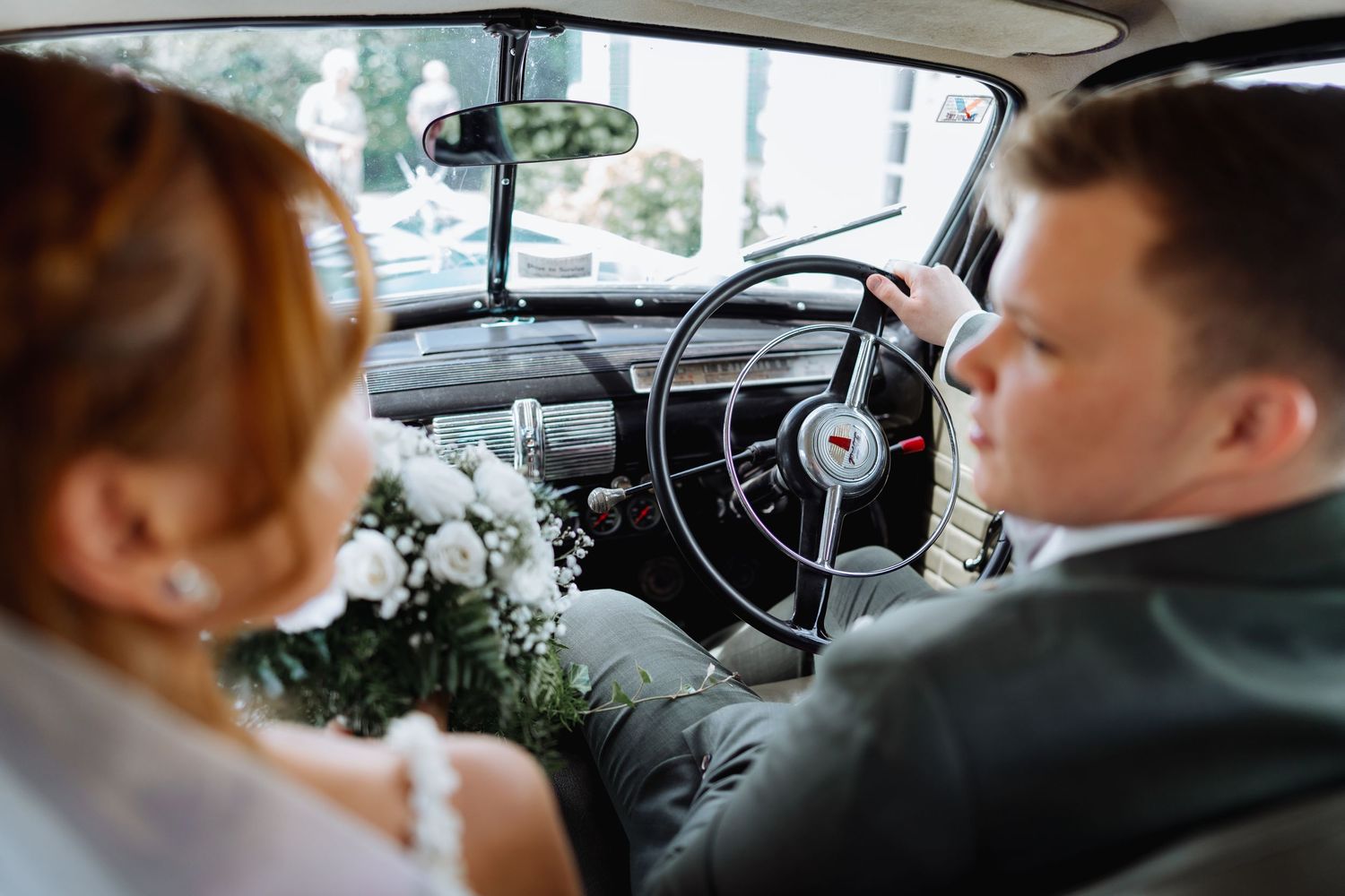 View from inside classic car showing dashboard and front seats.