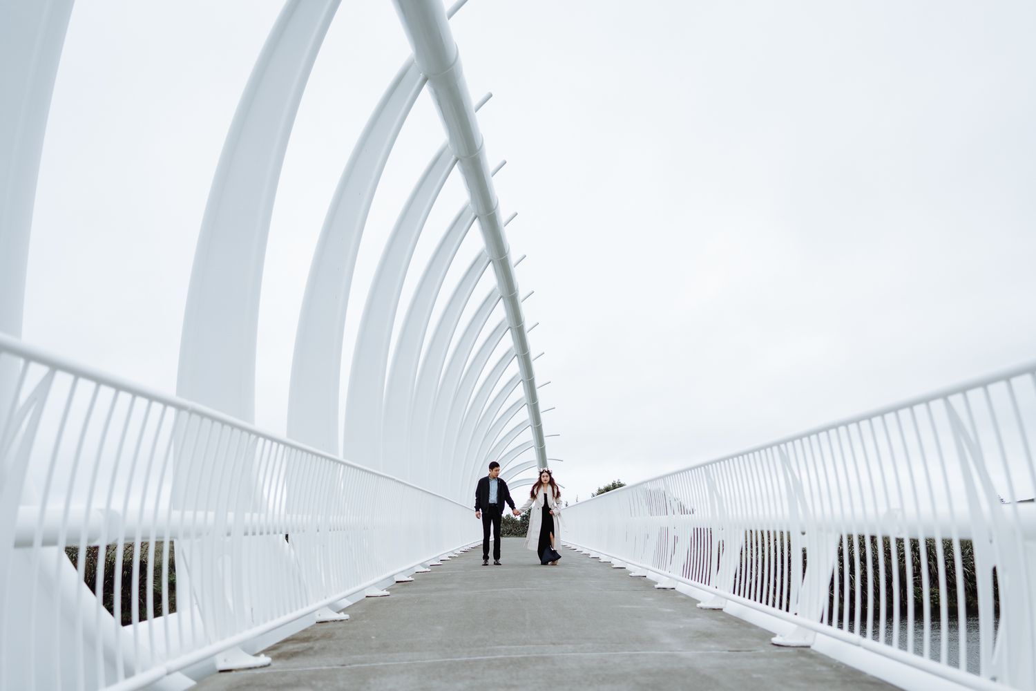 Two silhouettes walk through a bright white modern architectural corridor.