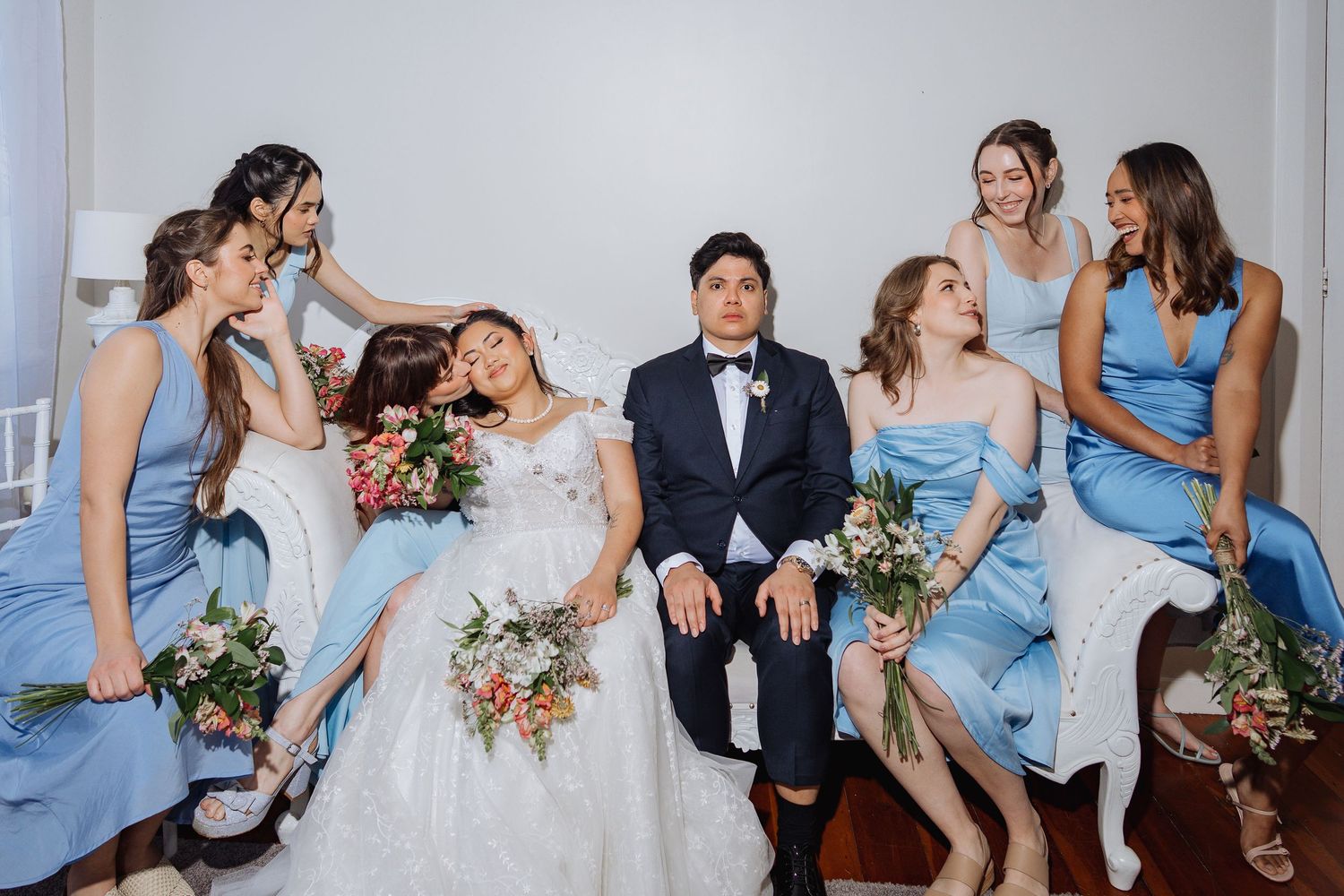 Wedding party in light blue bridesmaid dresses poses together indoors.