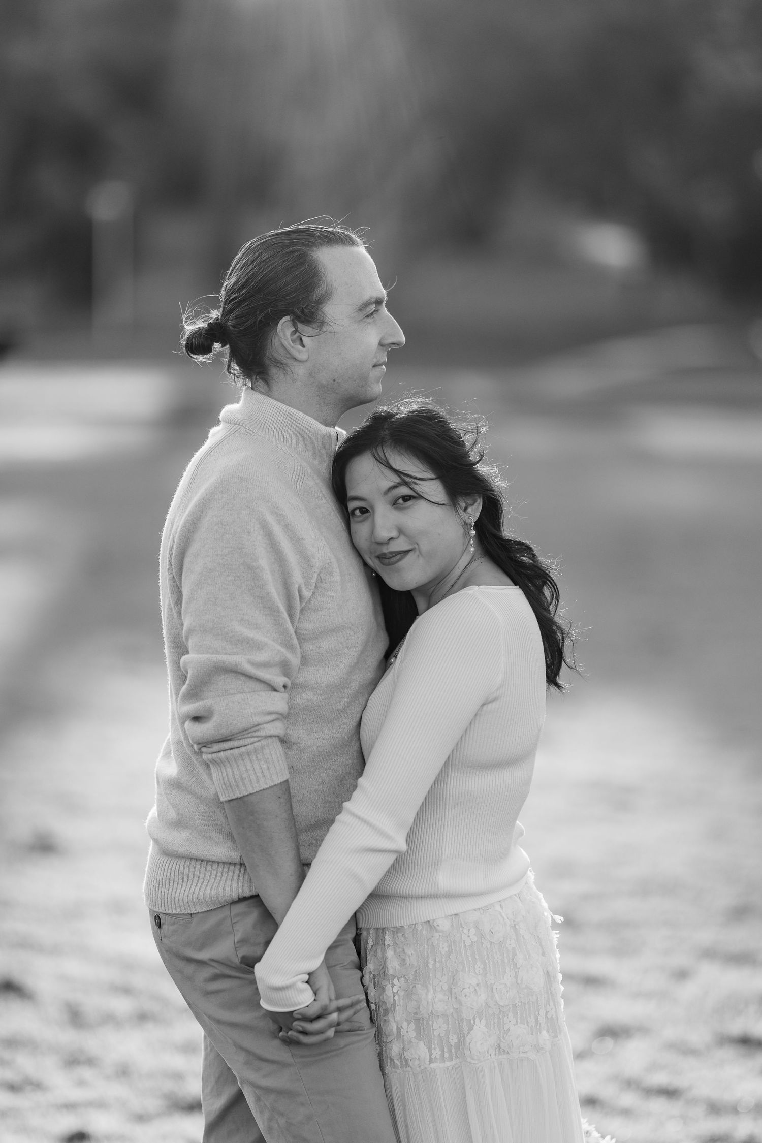 A couple embraces tenderly in a romantic black and white outdoor photoshoot.