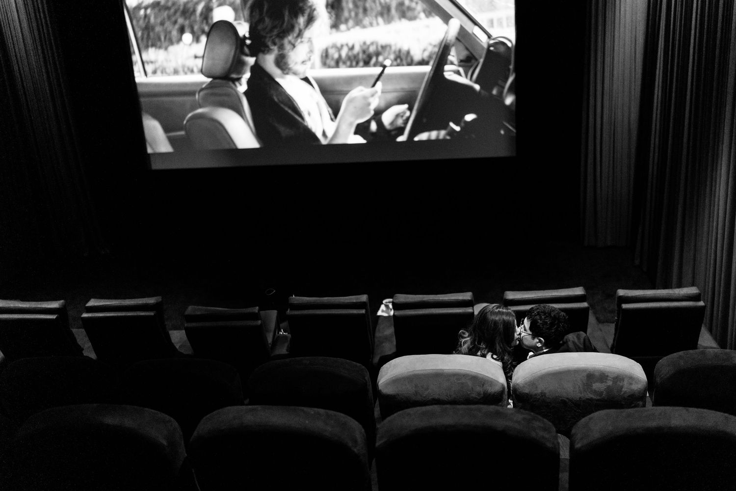 Empty theater seats with black and white film projected on screen.