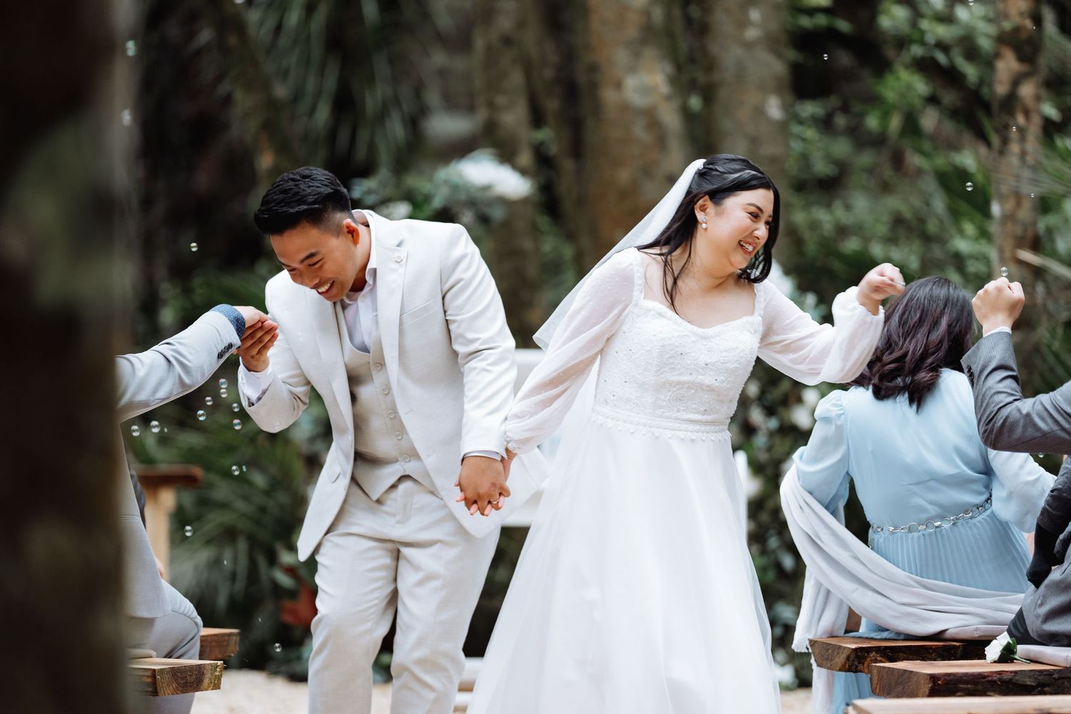 Wedding party dancing and celebrating in white attire at outdoor venue.