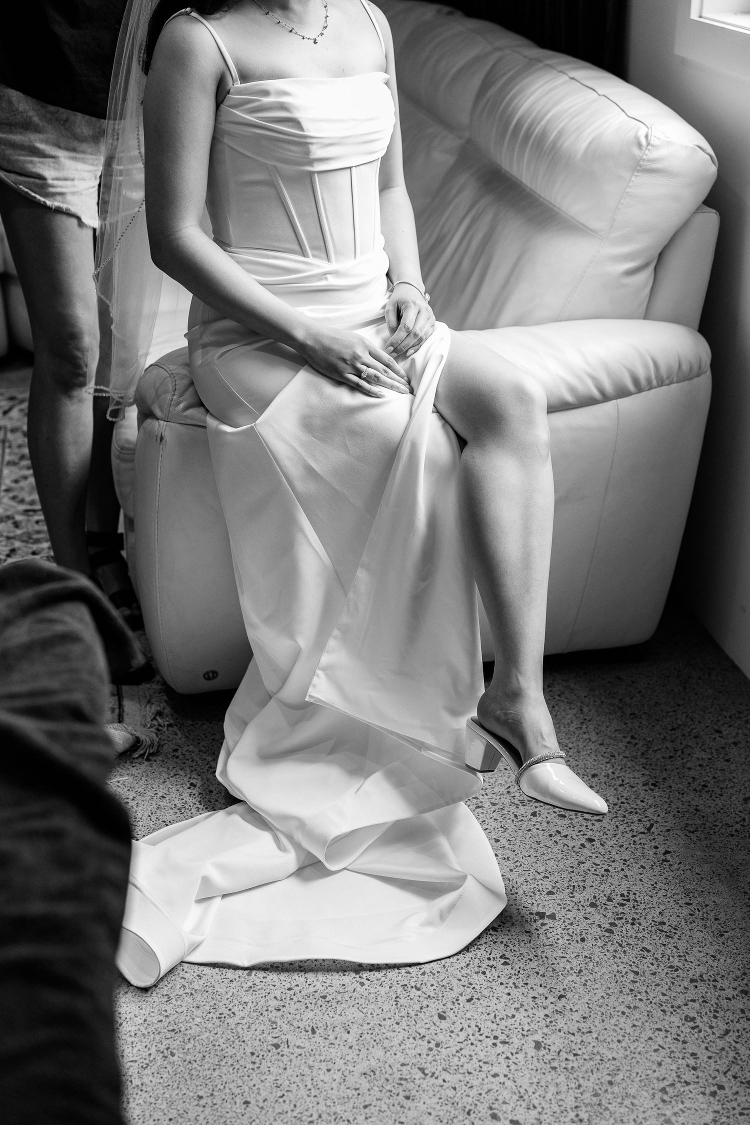 A white wedding dress draped elegantly across a light-colored couch.