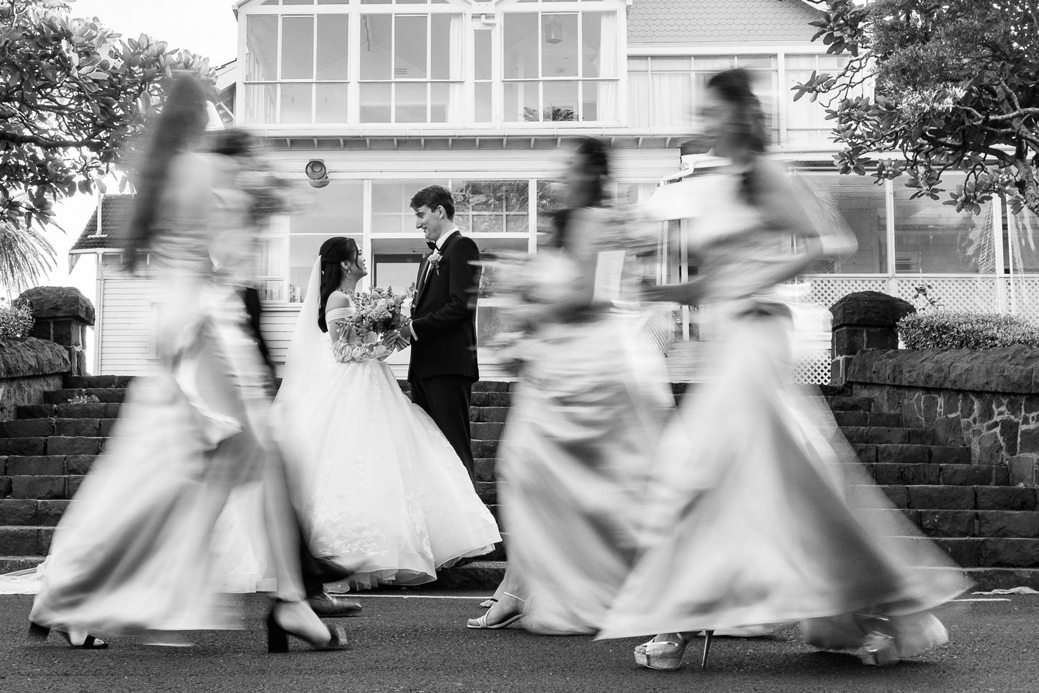 Motion blur captures bridesmaids running in a dynamic black and white wedding photo sequence.