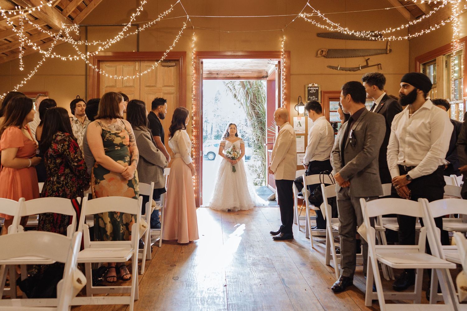 Wedding reception venue decorated with string lights and white tables.