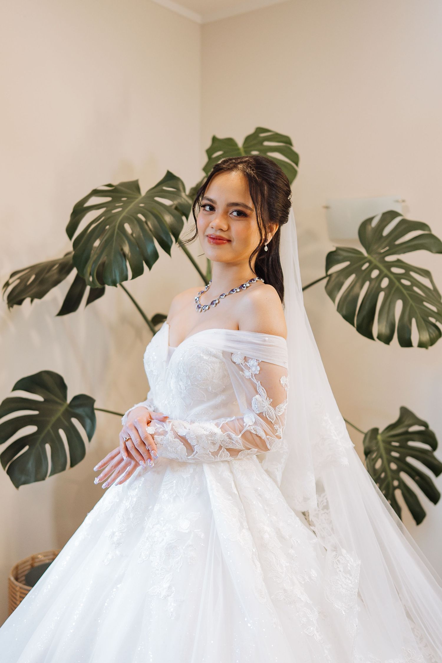 Wedding dress details with tropical monstera leaves decorating the background.