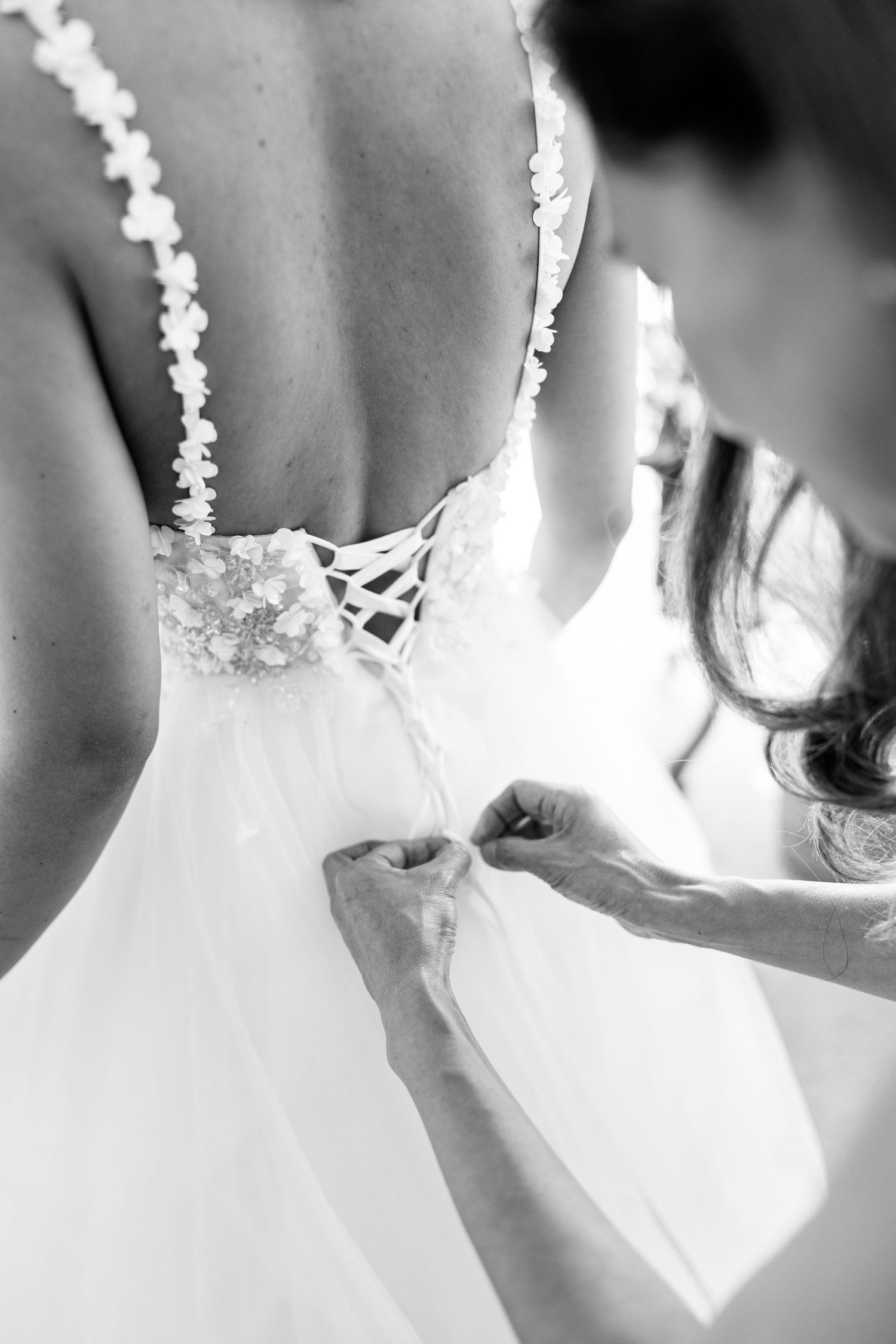Close-up details of a white lace wedding dress with delicate beading and embellishments.