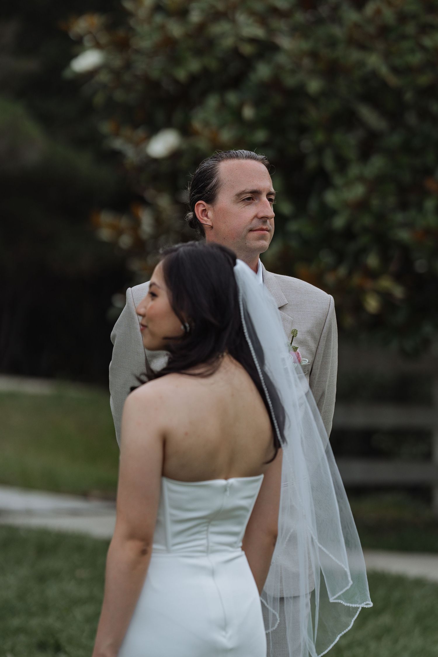 Newlywed couple in elegant attire share an intimate moment outdoors during their wedding photoshoot.