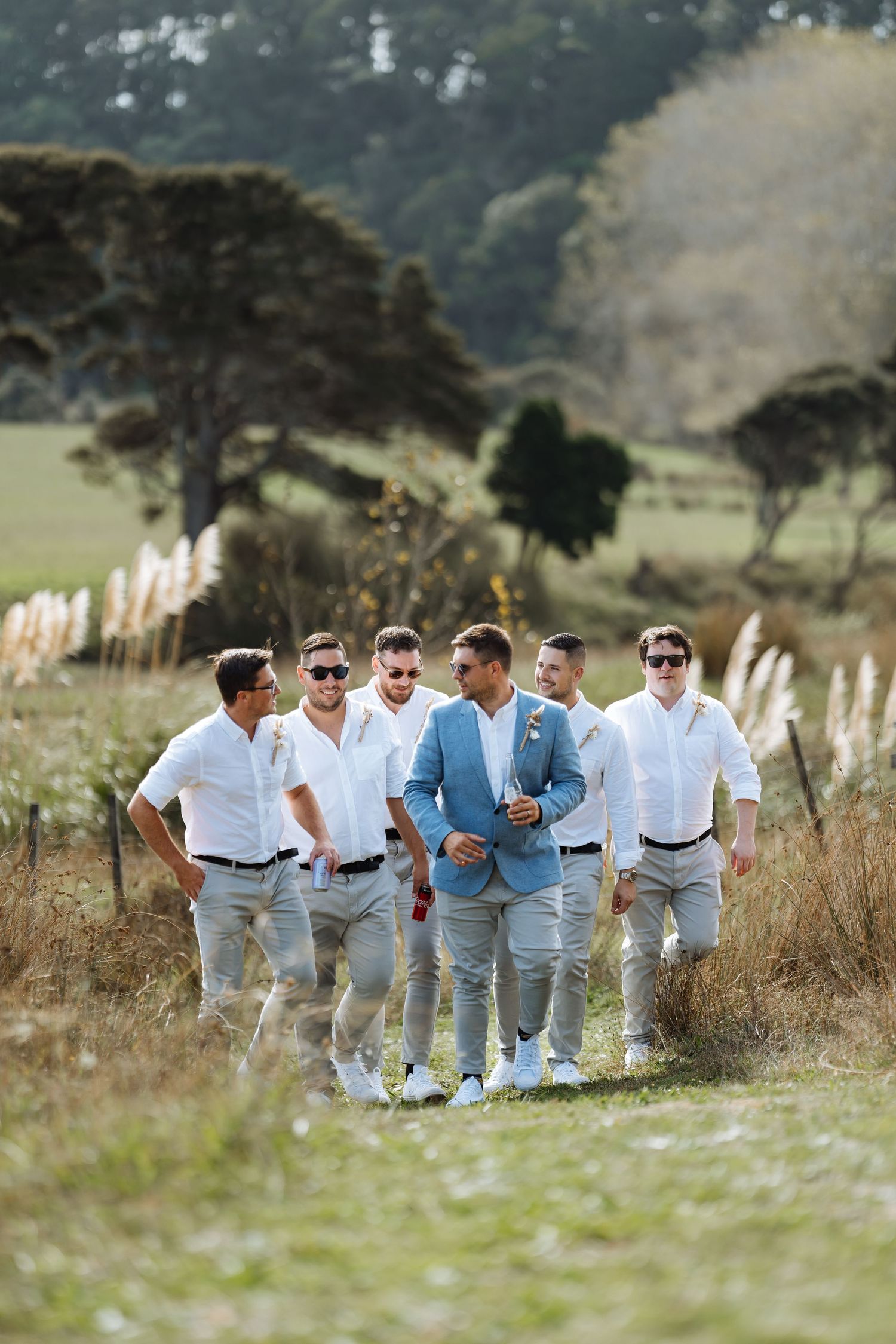Group walking together through a grassy field wearing coordinated white and blue outfits.