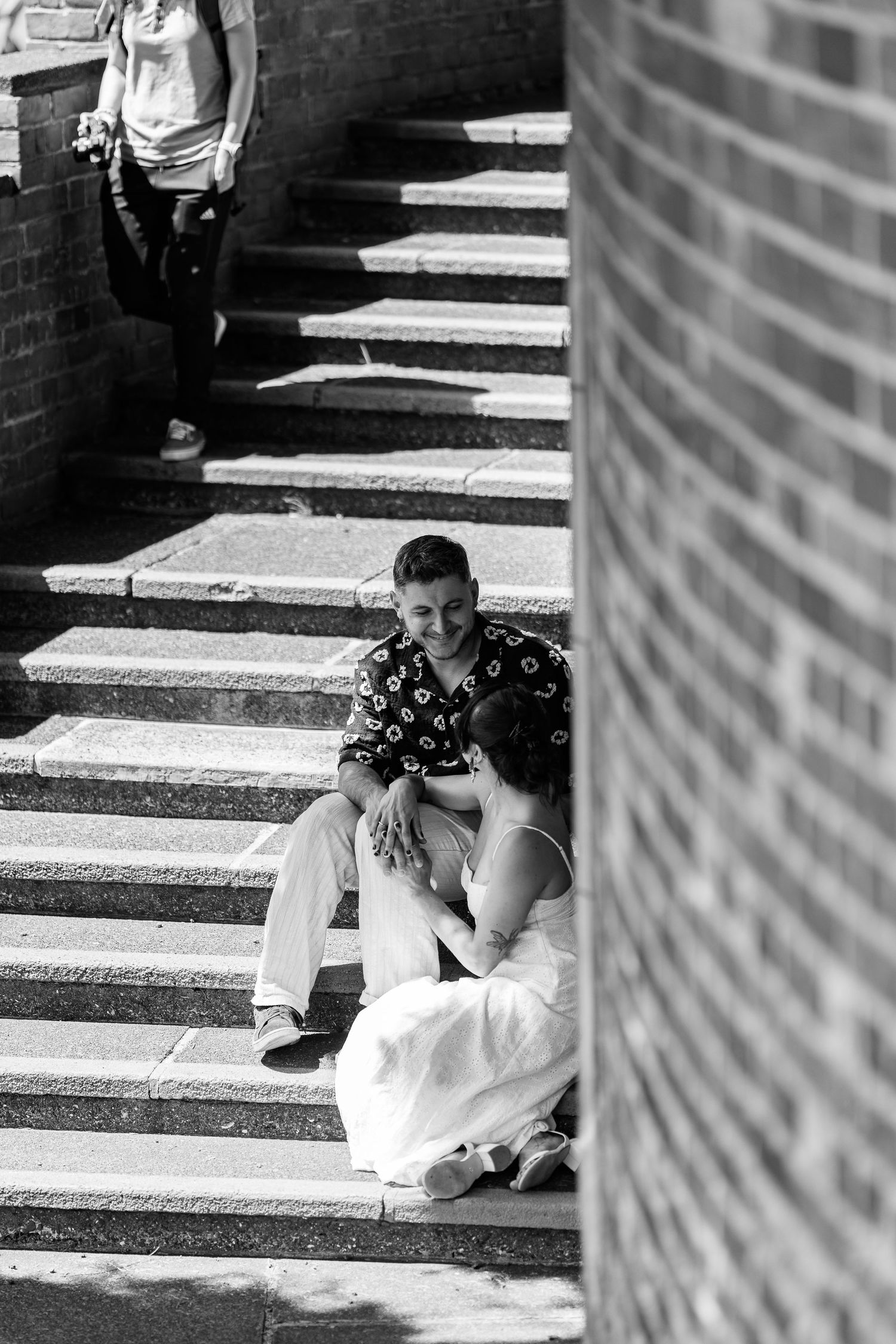 A black and white photo of a couple sharing an intimate moment on outdoor steps.