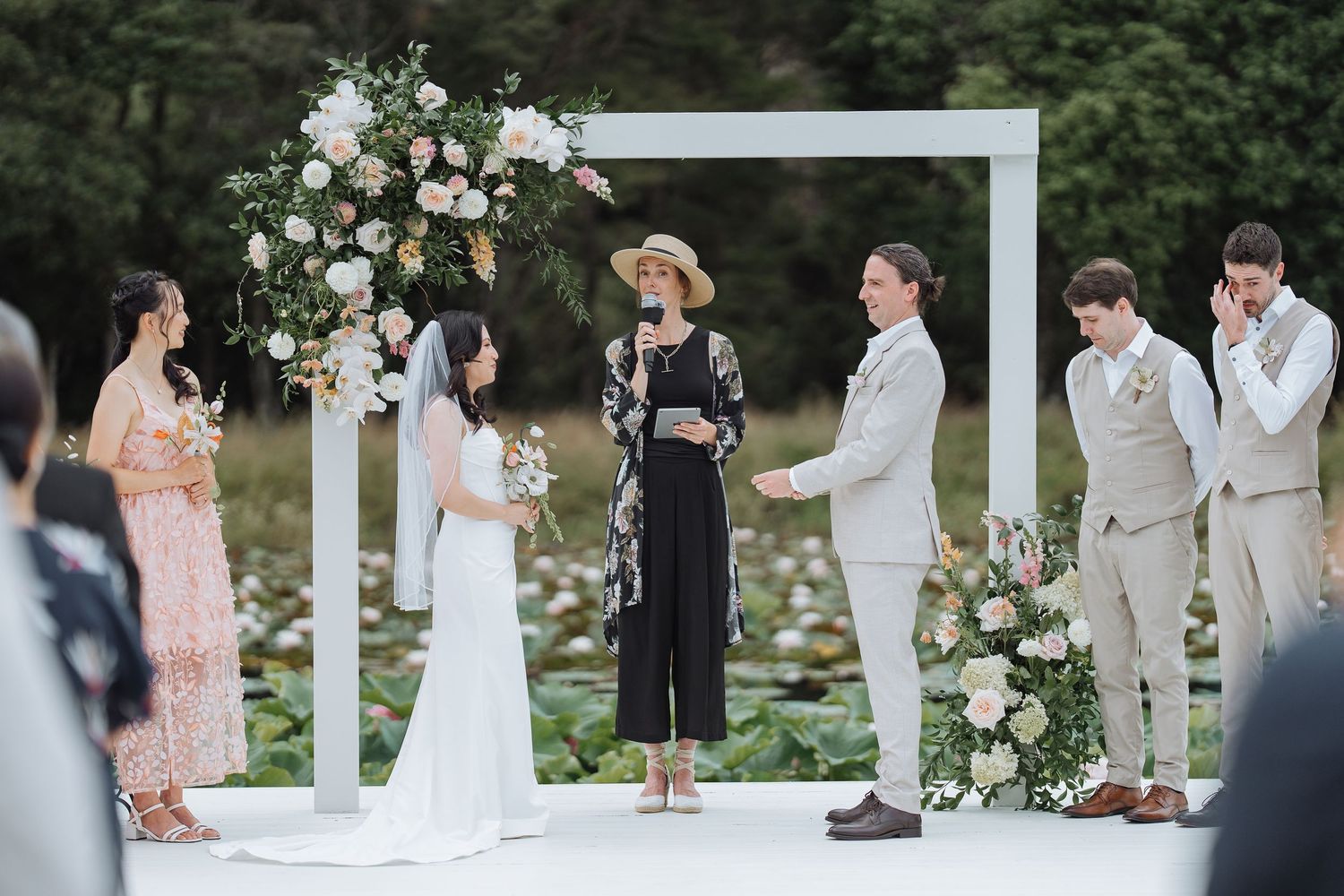 An outdoor wedding ceremony setup with floral arrangements and white decor.