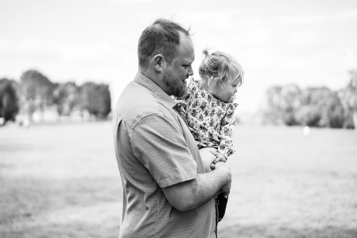 Black and white portrait of a family sharing tender moments outdoors.