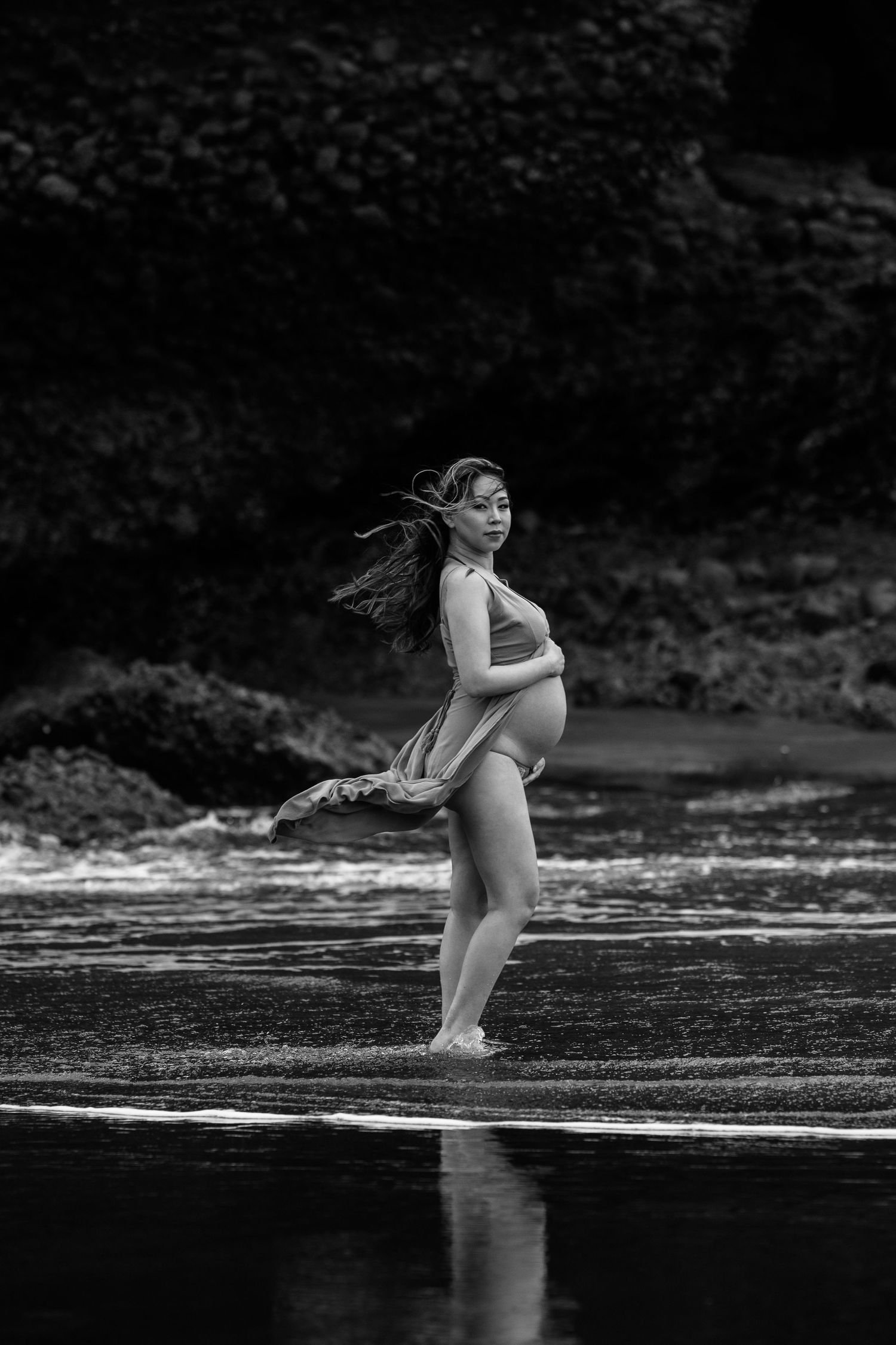 Artistic black and white photo of a figure in motion at the water's edge.
