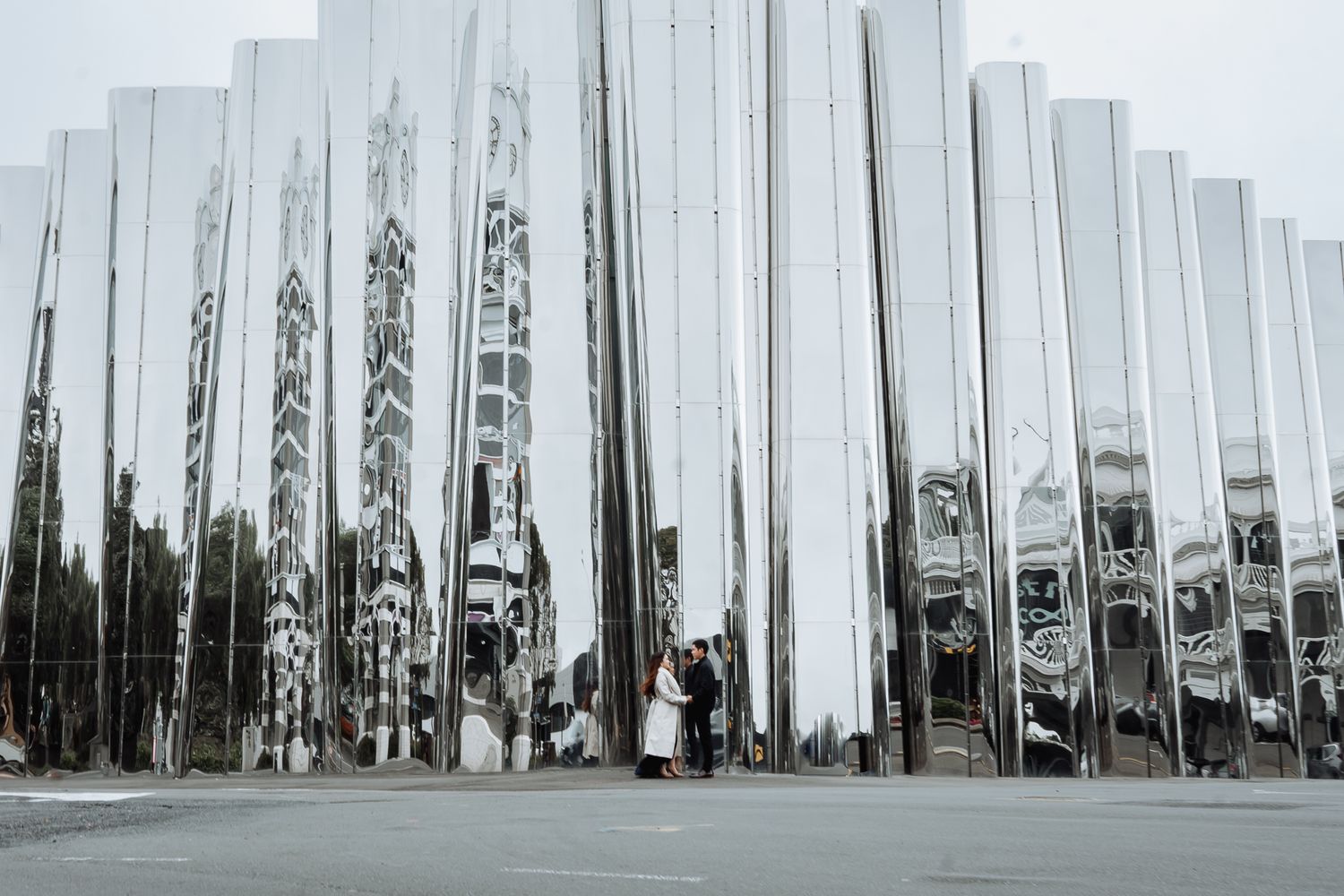 Modern art installation featuring tall white reflective pillars in urban setting.