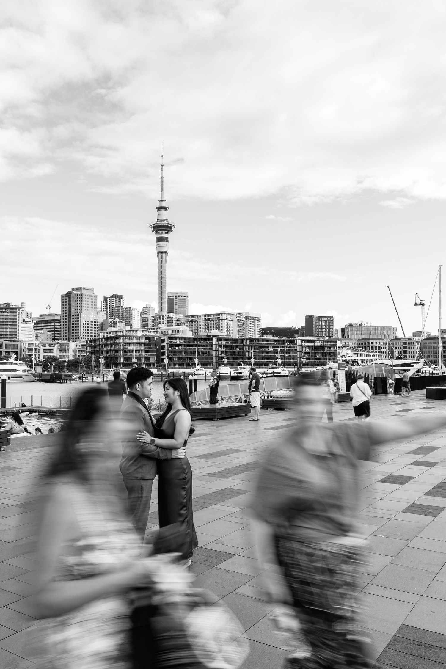 Black and white cityscape with motion blur of people walking along Auckland waterfront.