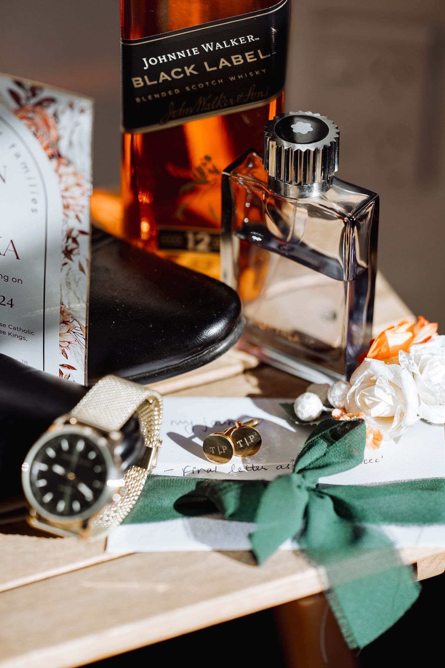 Johnnie Walker Black Label bottle with watch and accessories on green fabric.