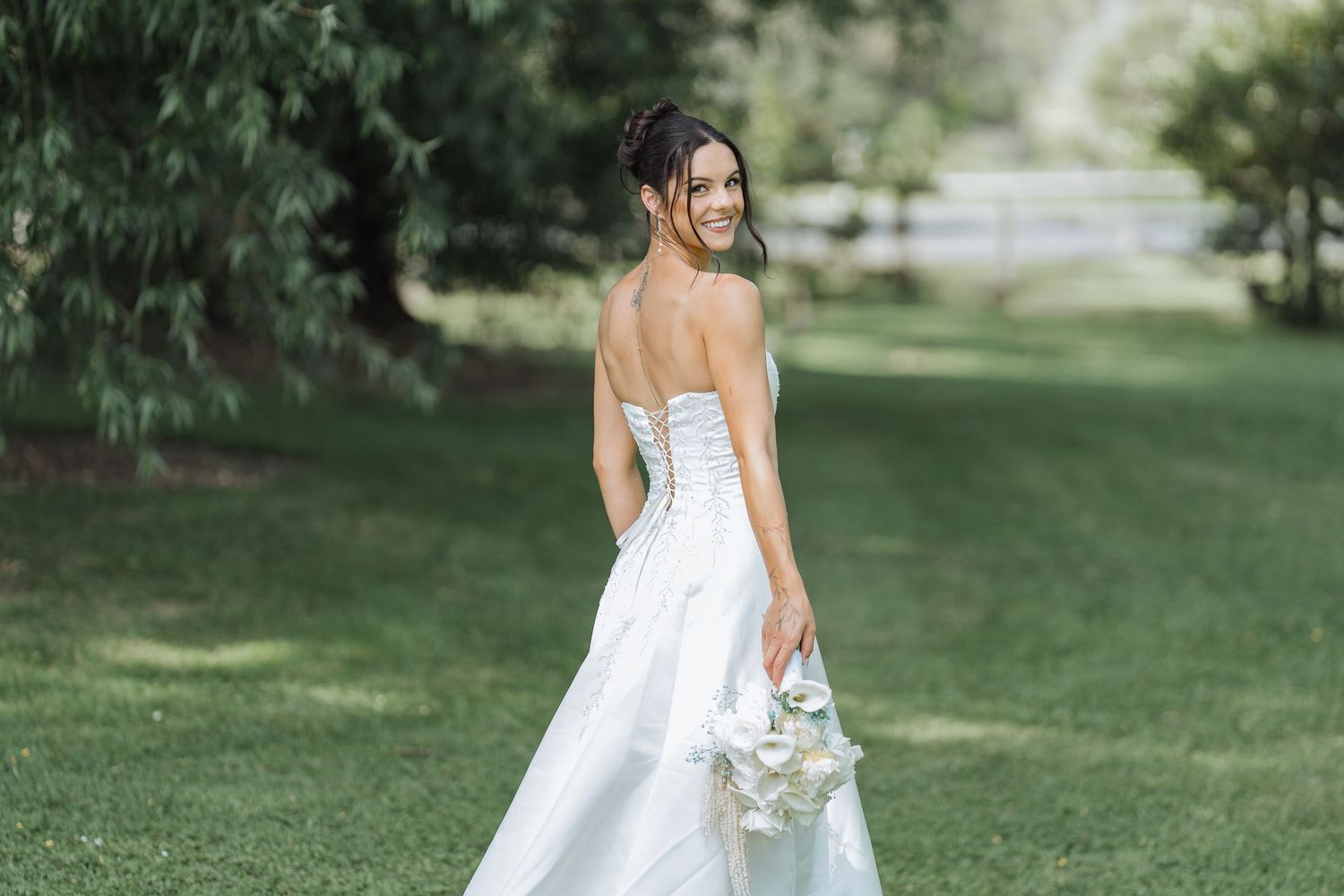 Elegant wedding dress photographed from behind in an outdoor garden setting.