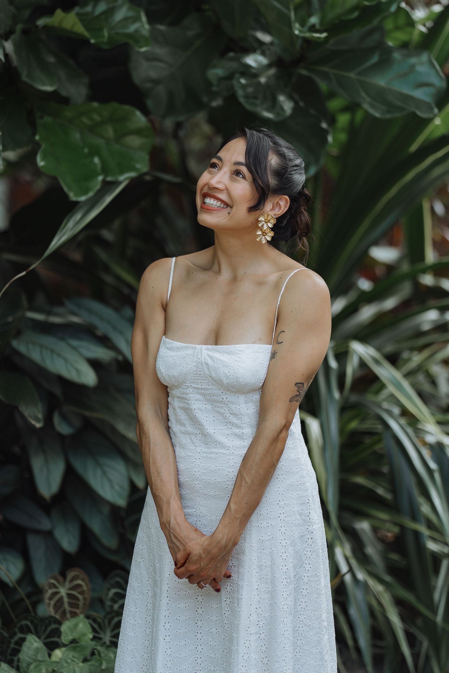 A joyful moment captured in a white dress against a backdrop of tropical plants.