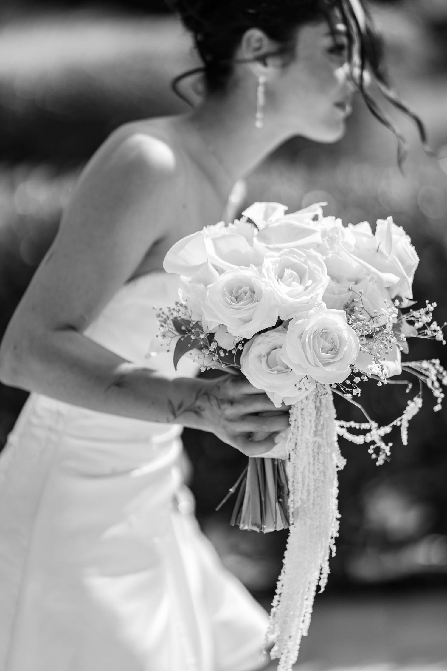 Elegant white bridal bouquet with roses and delicate lace details shown in black and white.