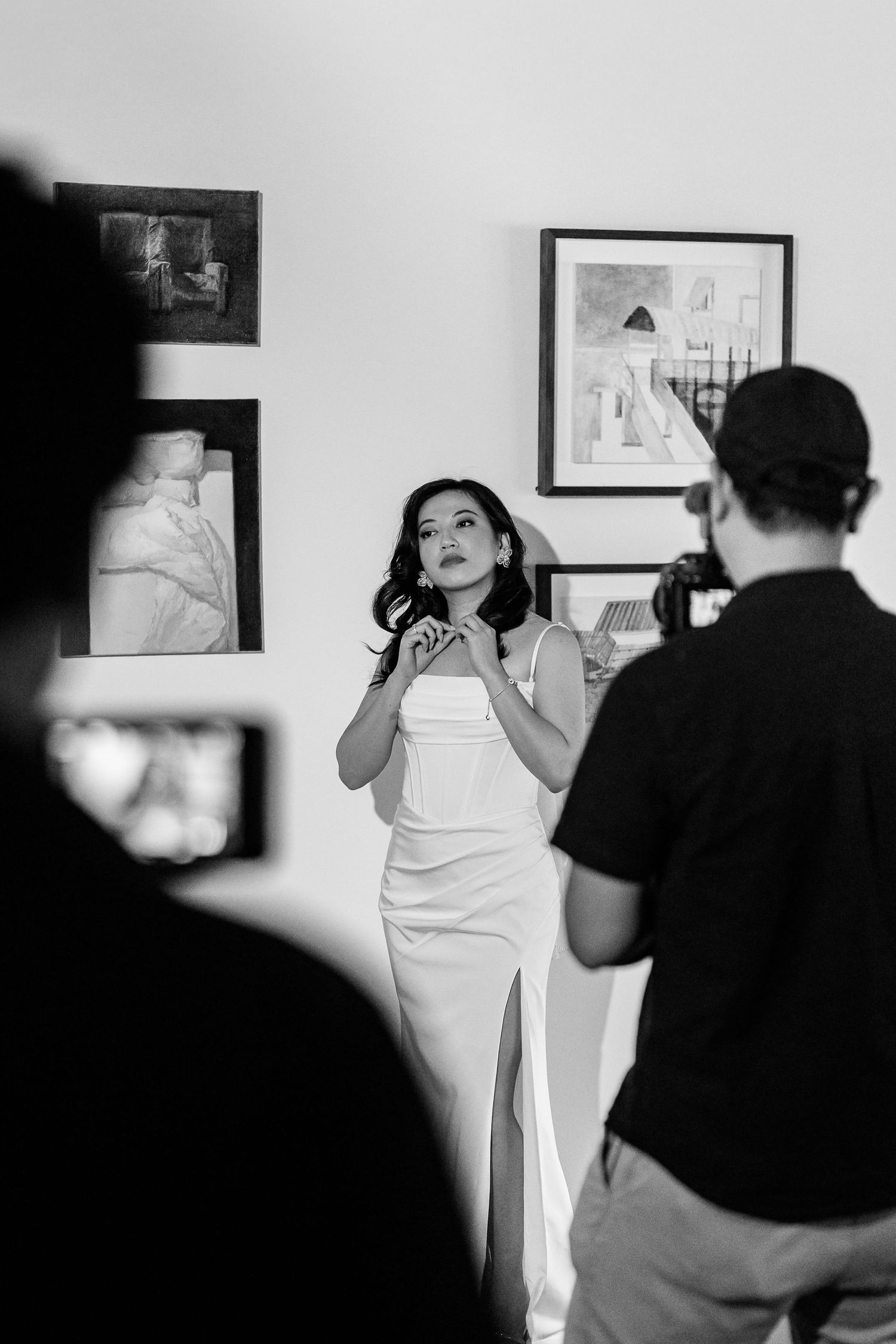 A photo session in progress with photographers capturing poses against a wall with artwork.