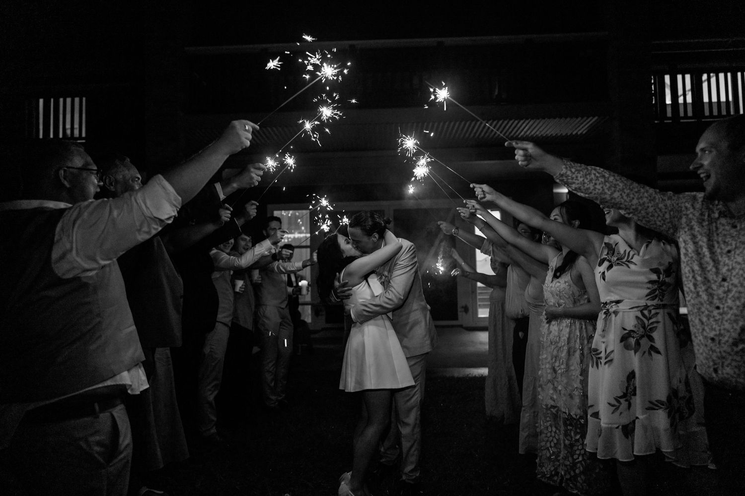 Nighttime celebration with sparklers illuminating a joyous crowd of dancing party guests.