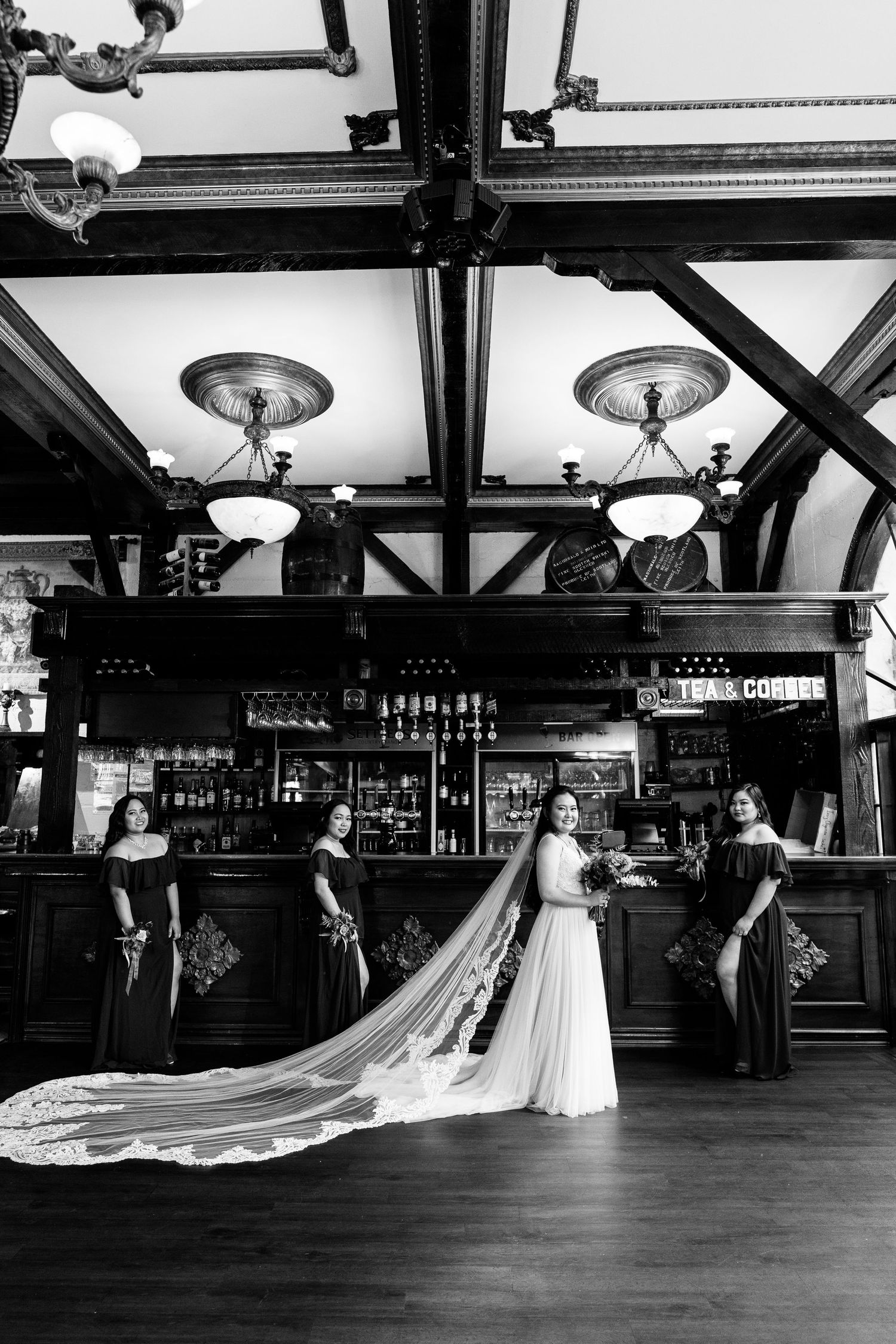 Black and white panorama of a vintage bowling alley with a bride in a flowing white dress.