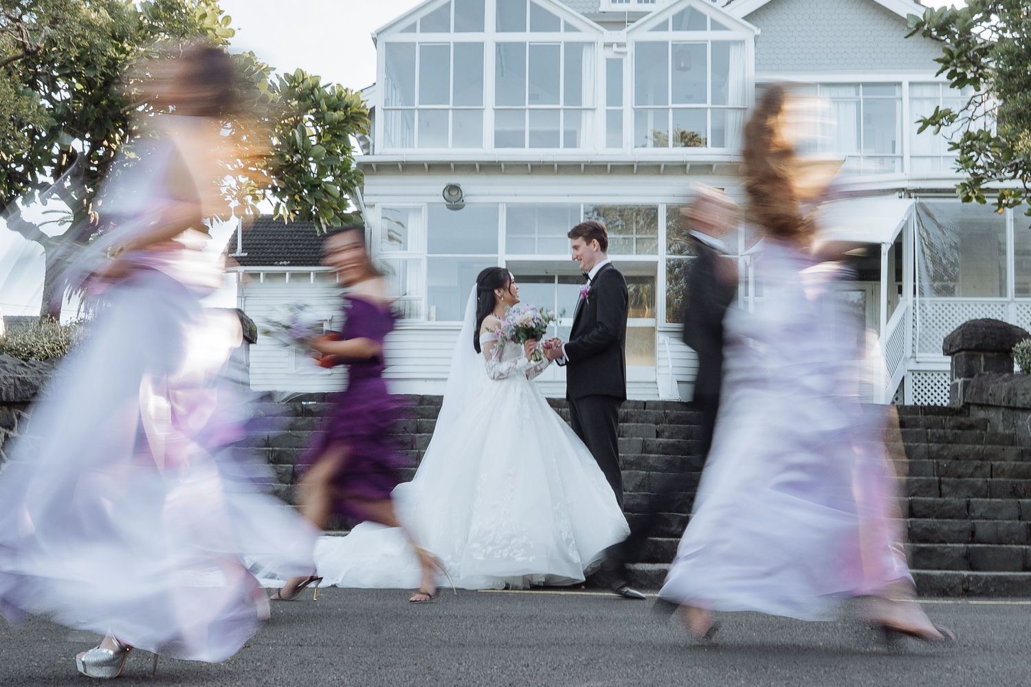 Motion blur sequence of people running and dancing outside a white house.