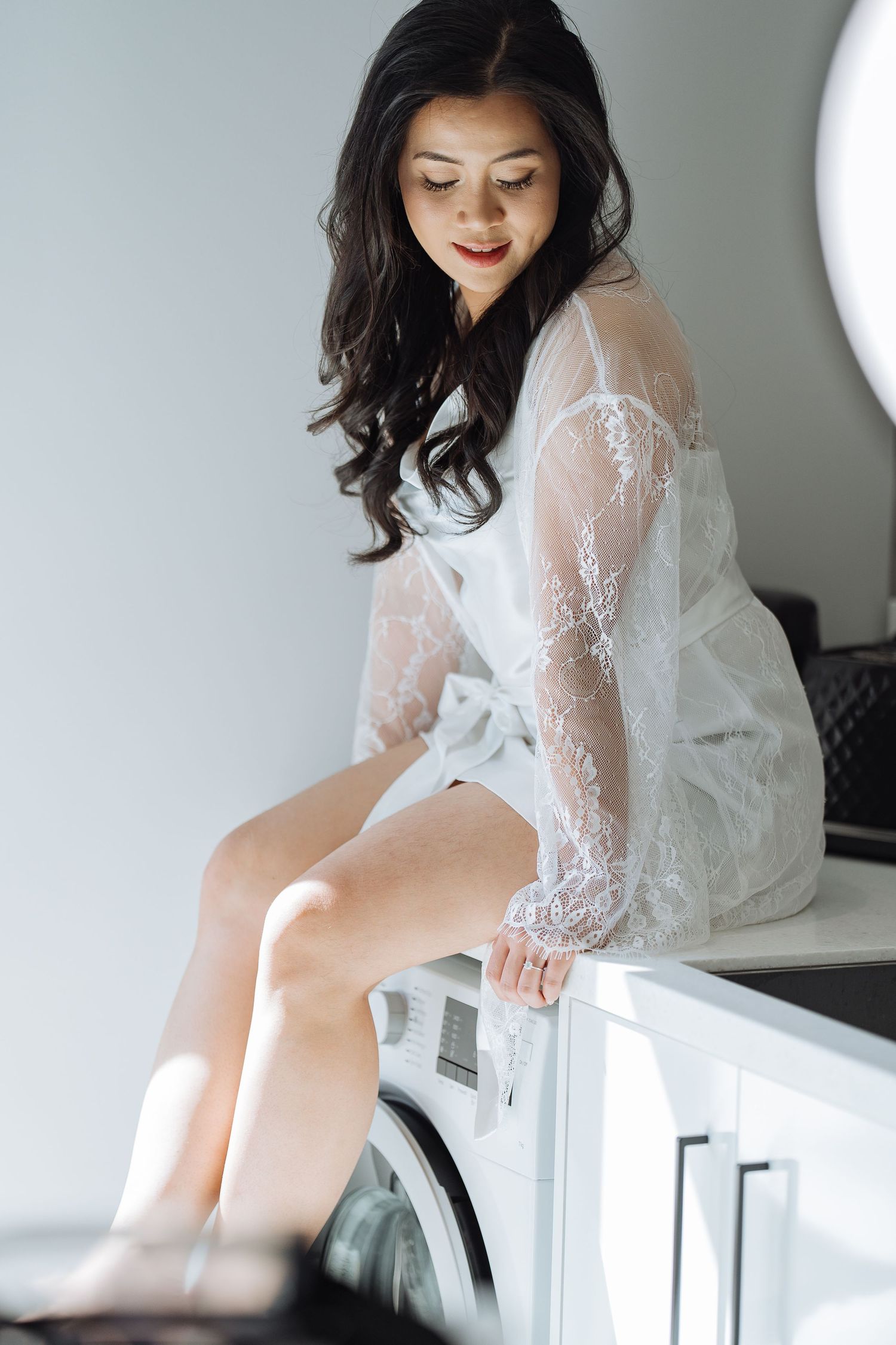 Elegant white lace bridal boudoir session in a bright room.