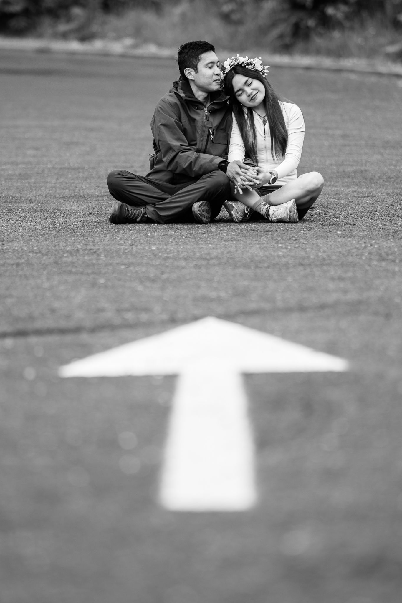 Couple lying on grass with white arrow marking in foreground.