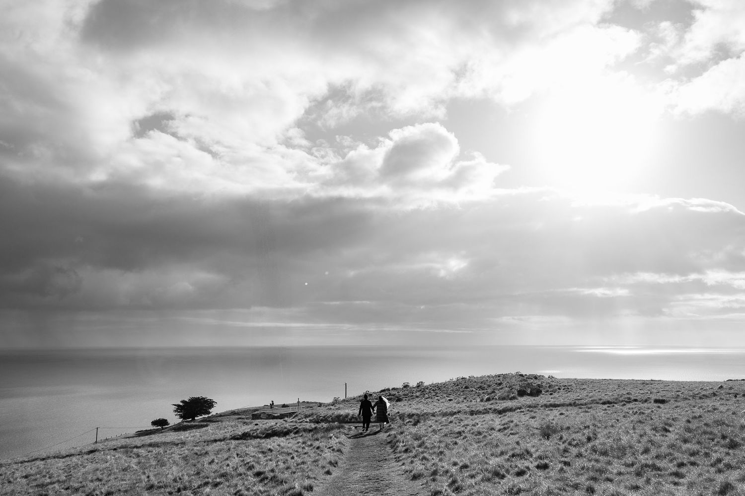 Dramatic cloudy skies over a coastal hillside landscape with ocean views.