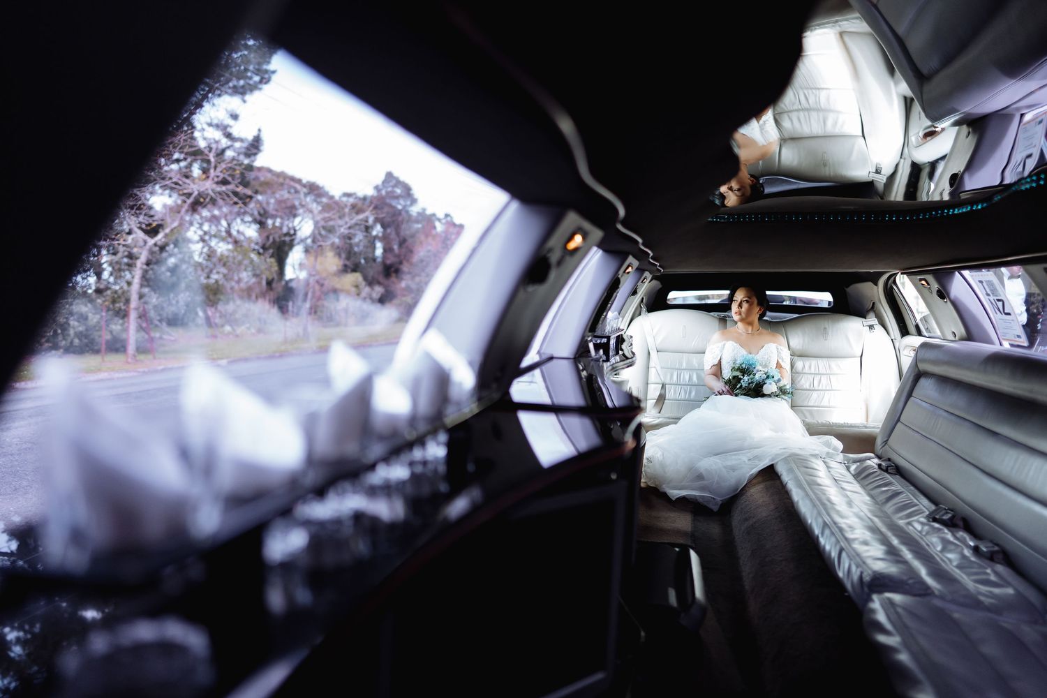 Interior view of wedding limousine with white leather seats and decorative lighting.
