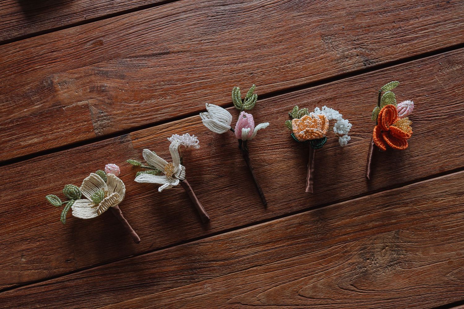Small flowers and petals arranged in a line on dark wooden floorboards.