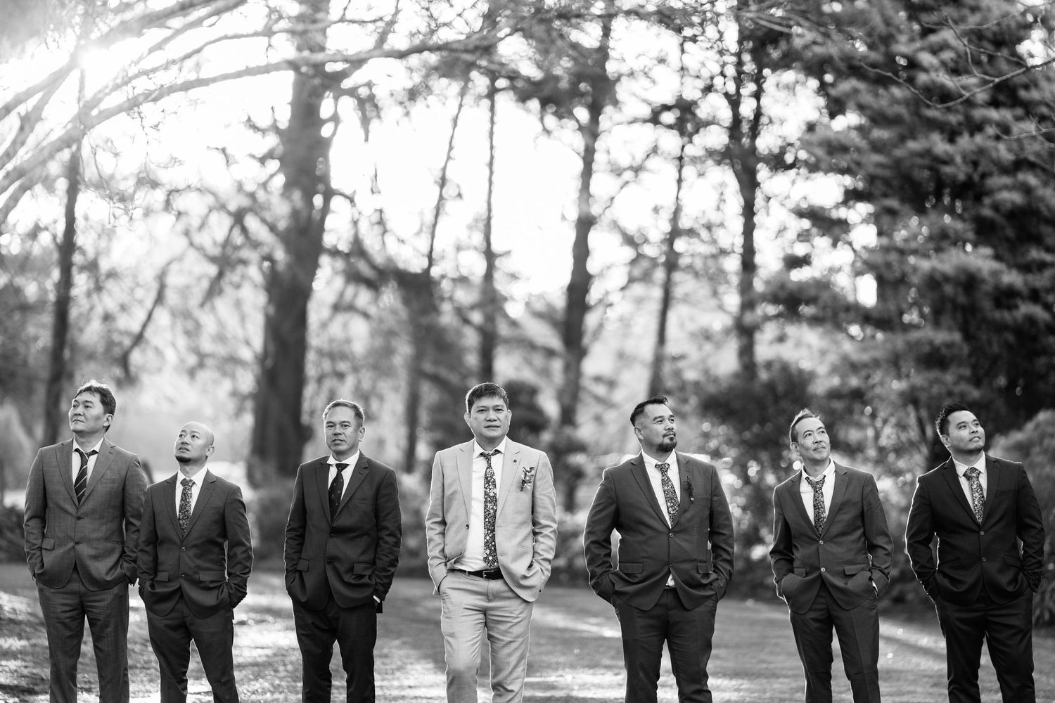 Classic black and white photo of groomsmen lined up outdoors.