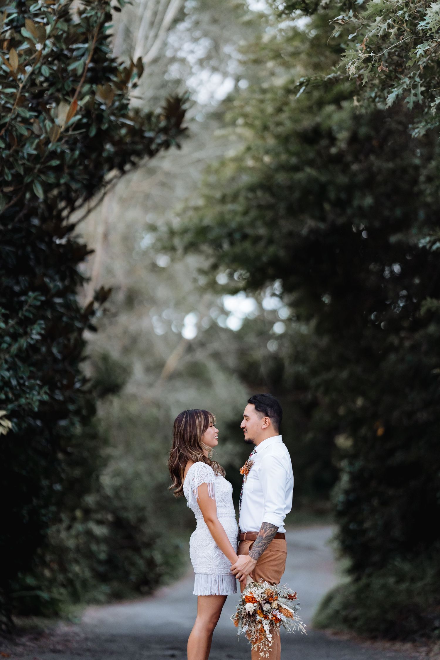 A couple shares intimate moments along a tree-lined pathway during their engagement session.