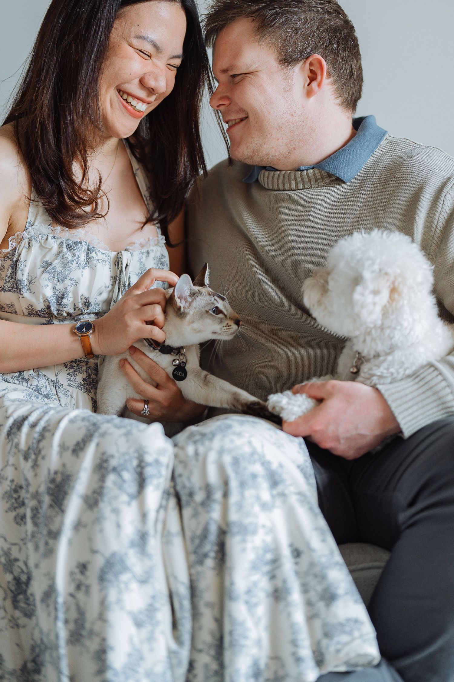 Couple cuddling with white fluffy dog on couch.