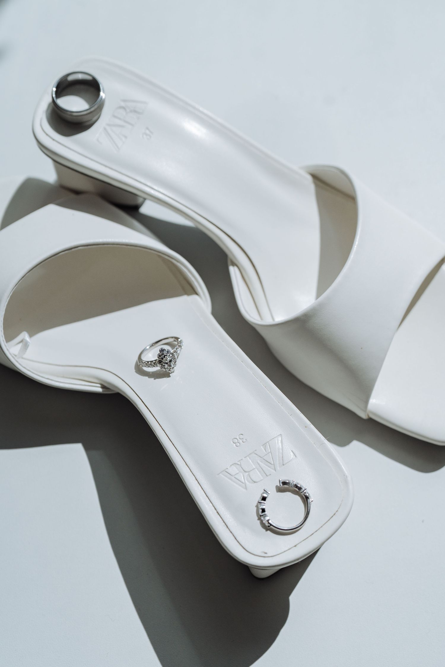 White designer shoes with elegant details photographed on light background.