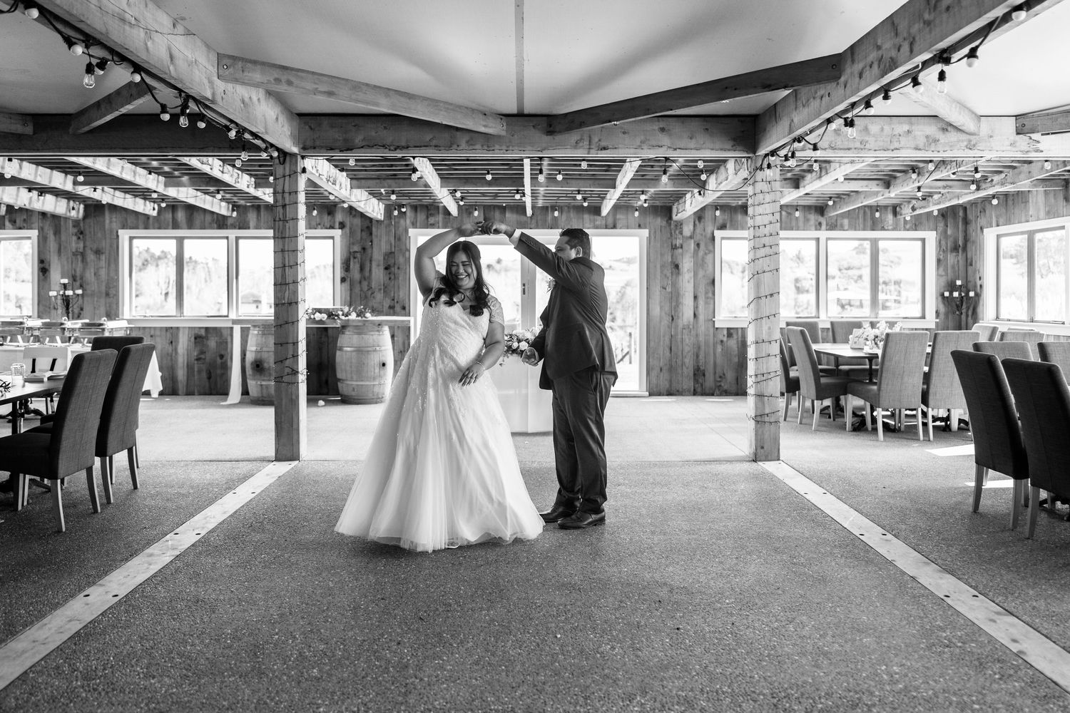 Spacious wedding reception venue with elegant table settings and hanging lights.