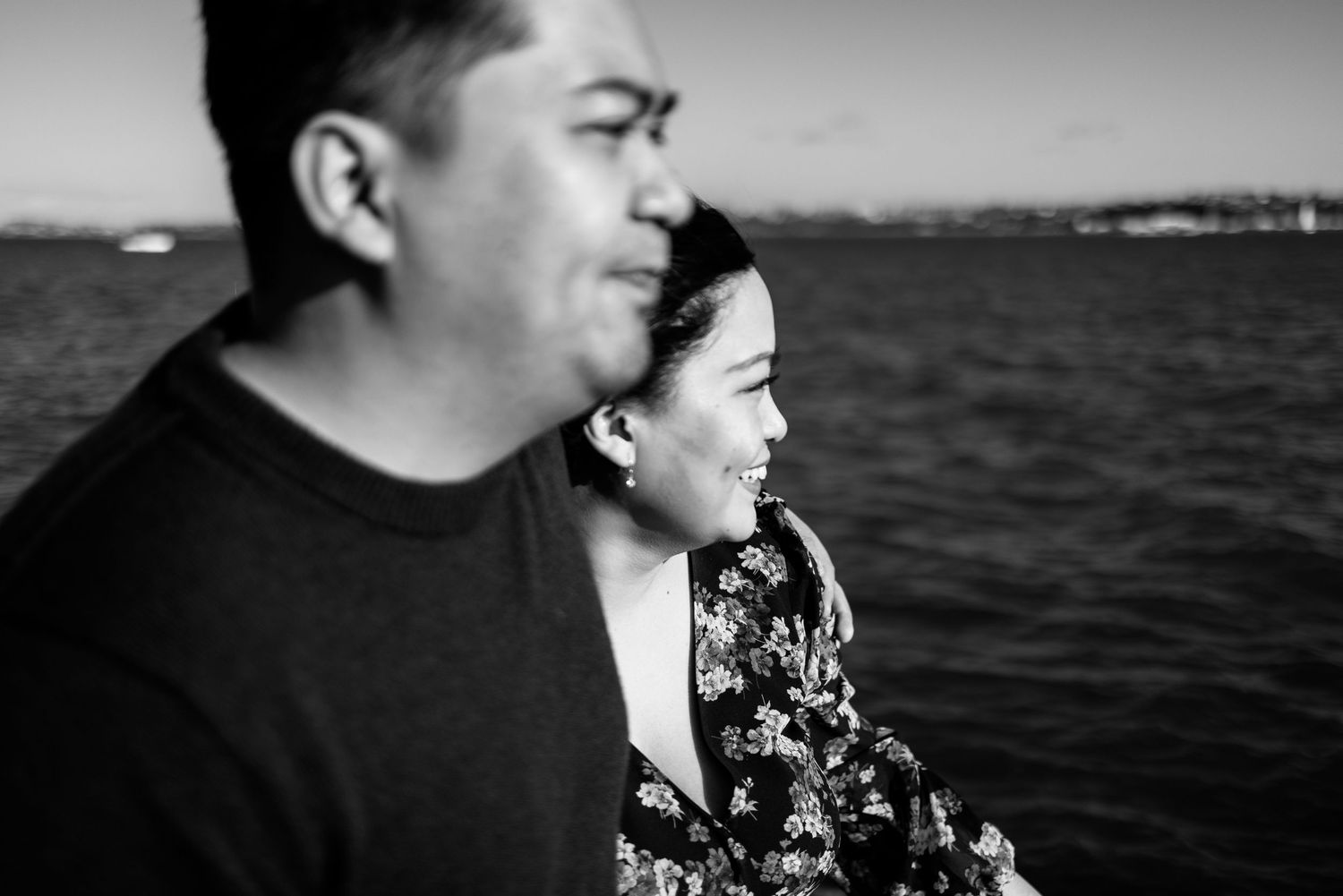 A black and white portrait by the waterfront on a bright day.