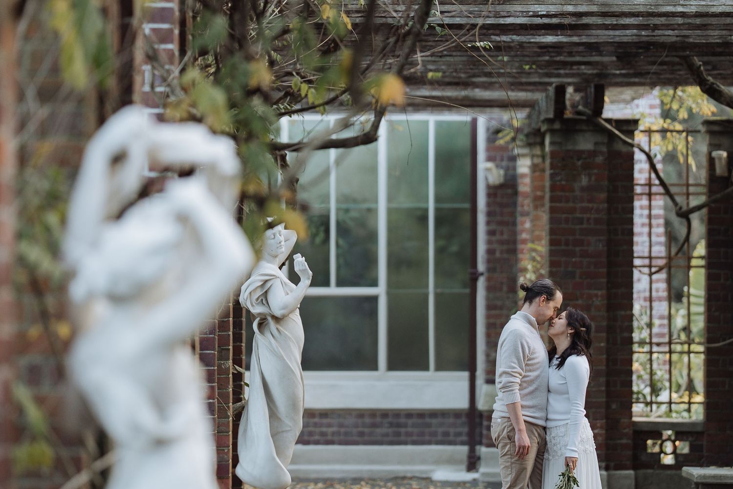 A romantic garden scene with classical statues and natural greenery.