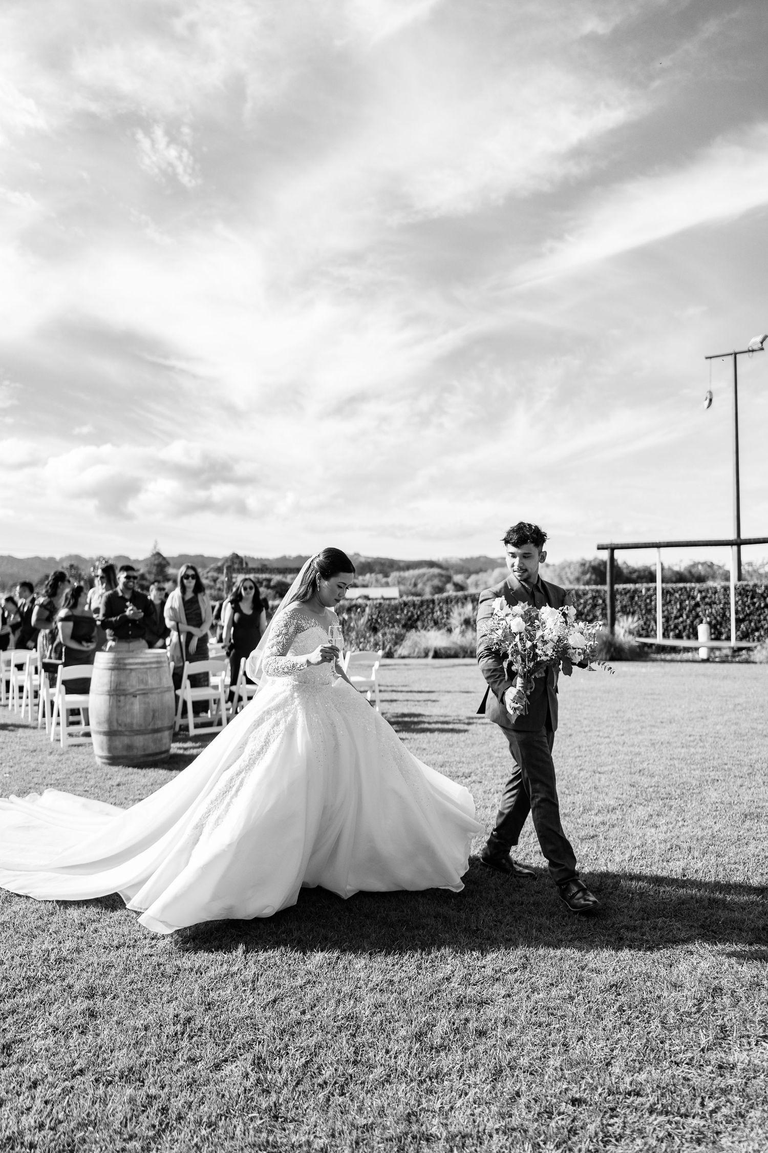 Wedding celebration taking place in an outdoor field with scenic mountain views in black and white.
