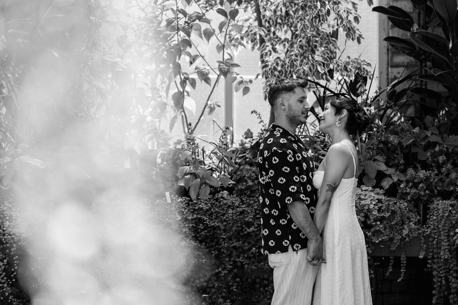 Black and white portrait of couple sharing tender moments in a garden setting.