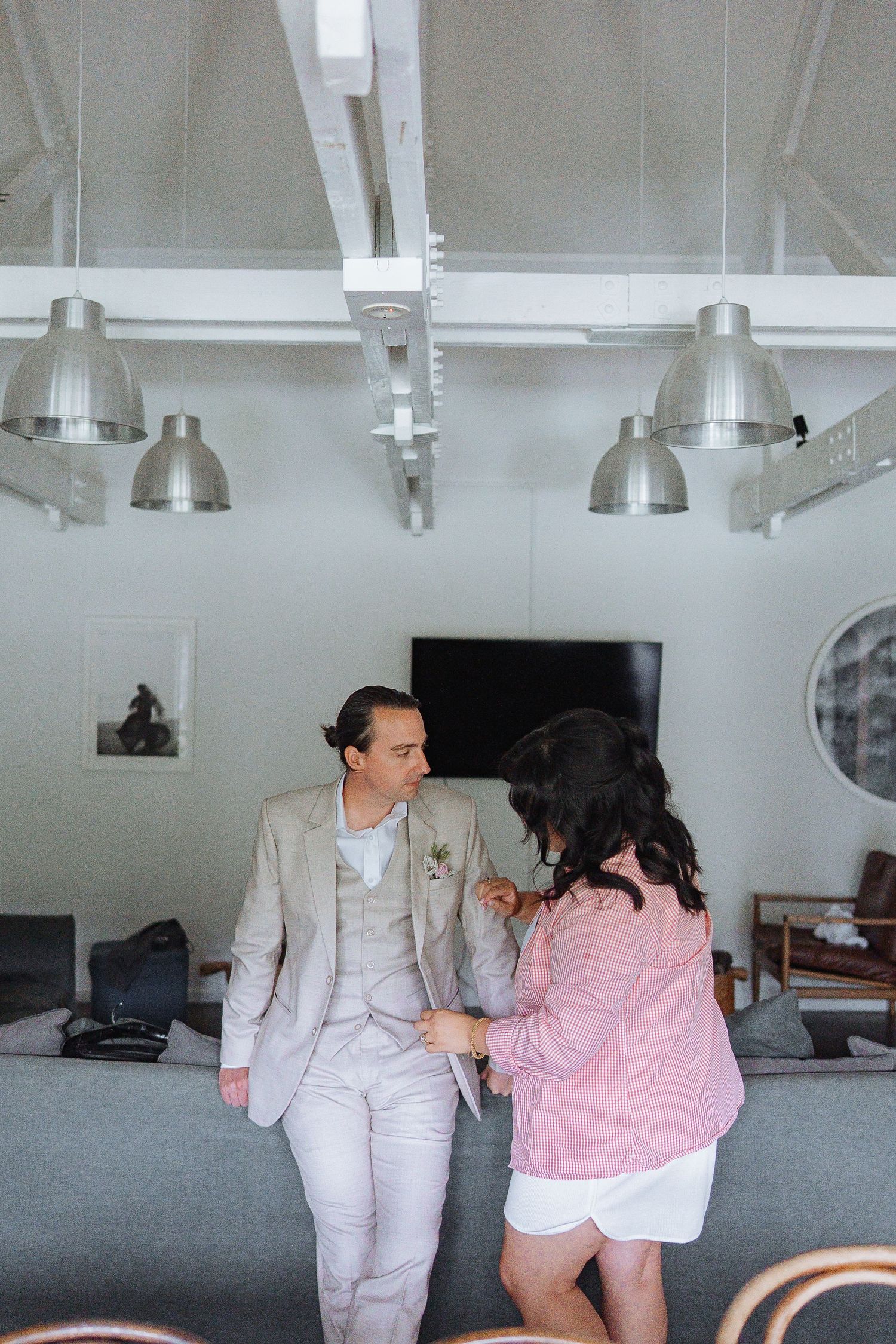 Sequence showing playful interaction between two people in light colored outfits under industrial lighting.