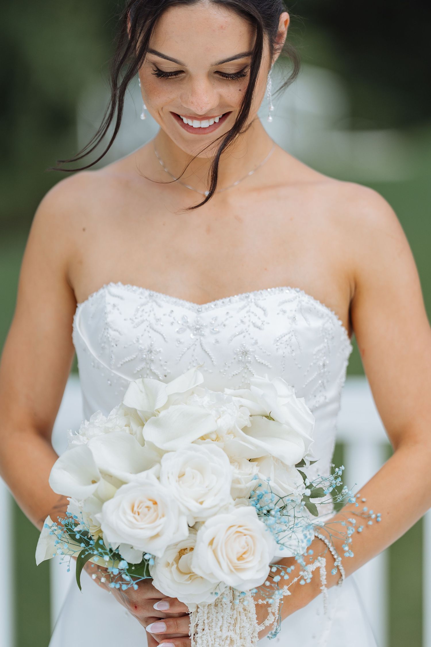 Beautiful white roses and delicate floral bouquet with soft greenery accents against a blurred natural background.